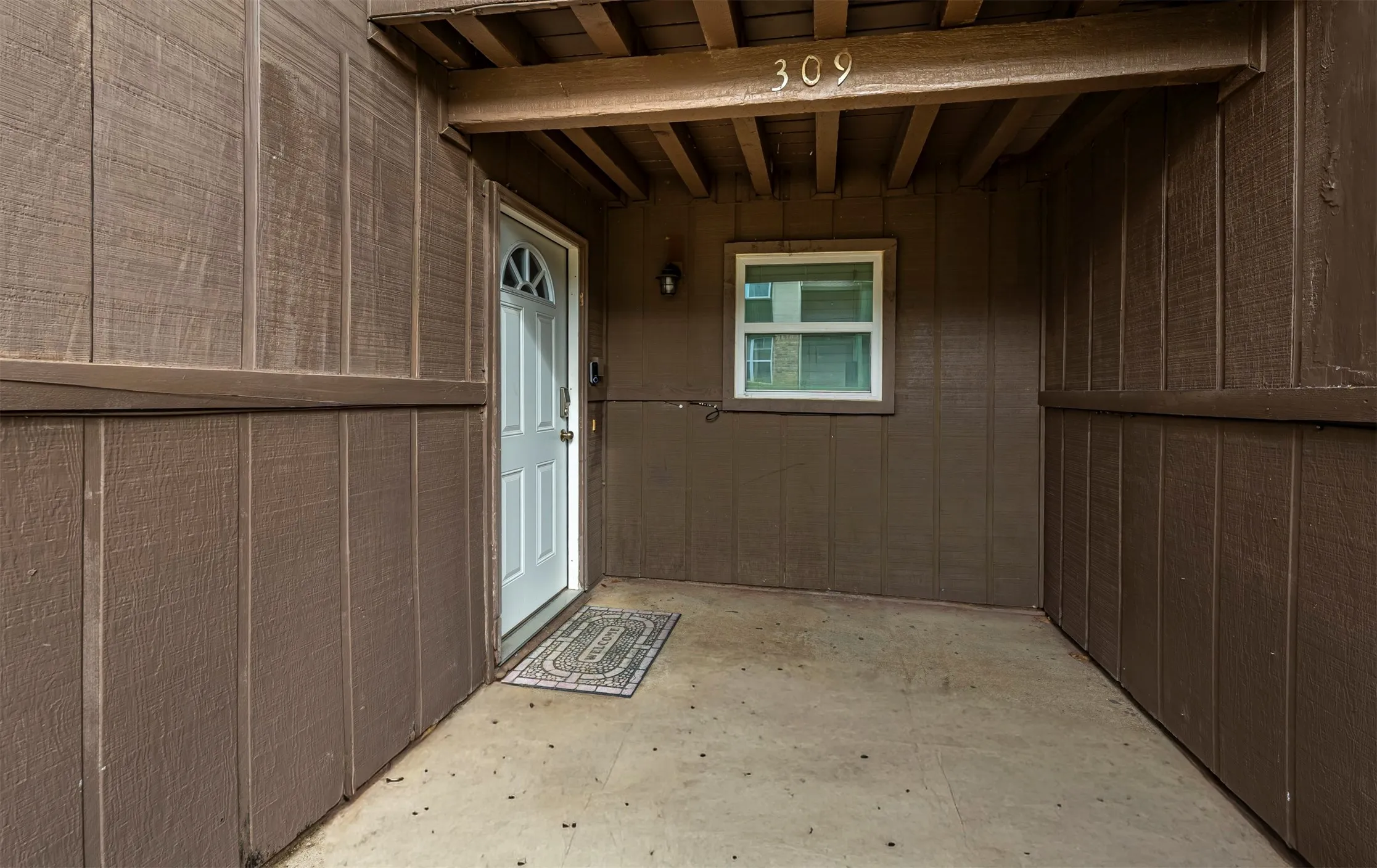 Entry with a white door featuring an arched window detail, covered porch, and a dedicated address marker