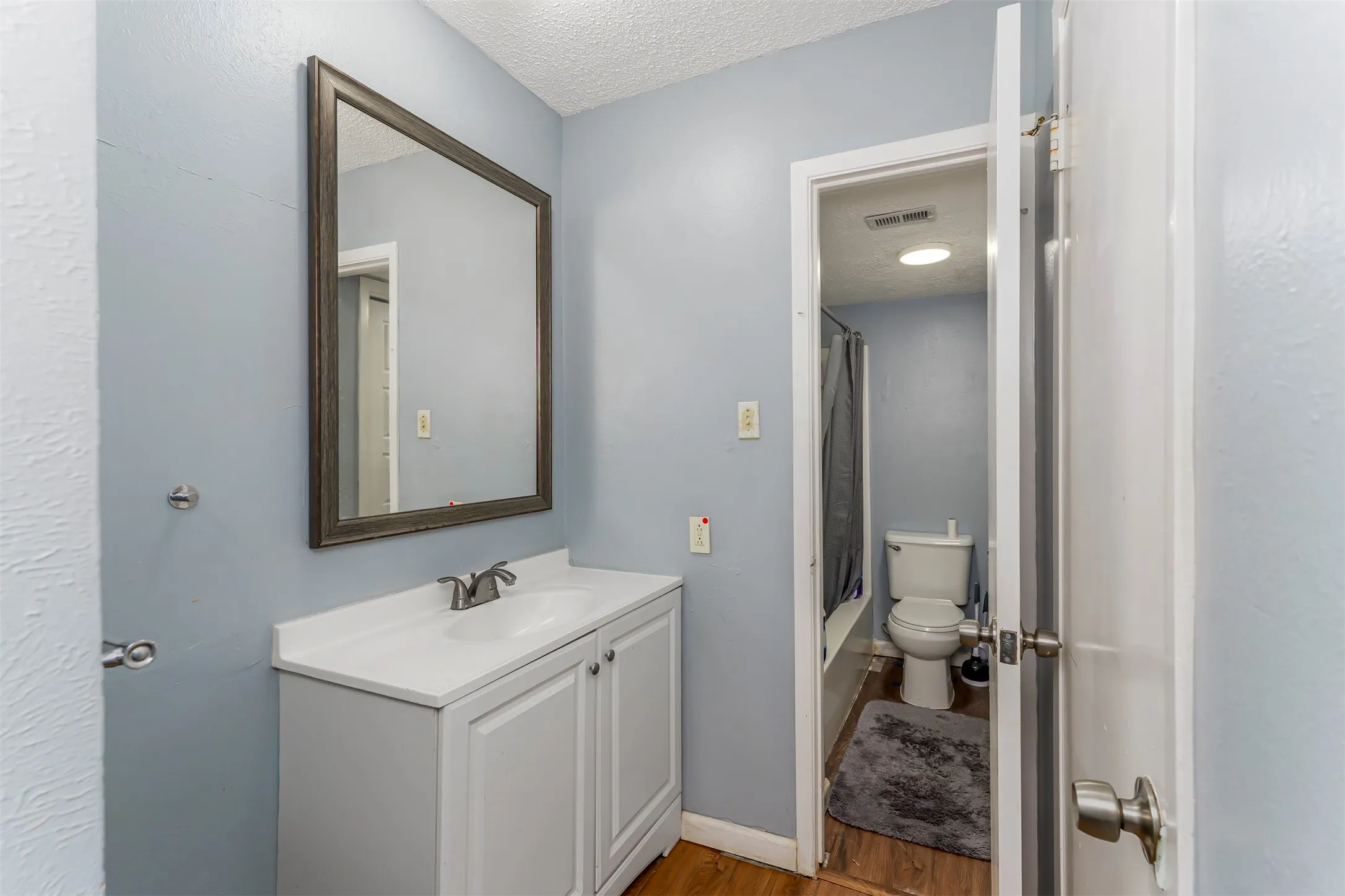 White vanity with an integrated sink, framed mirror, and chrome faucet