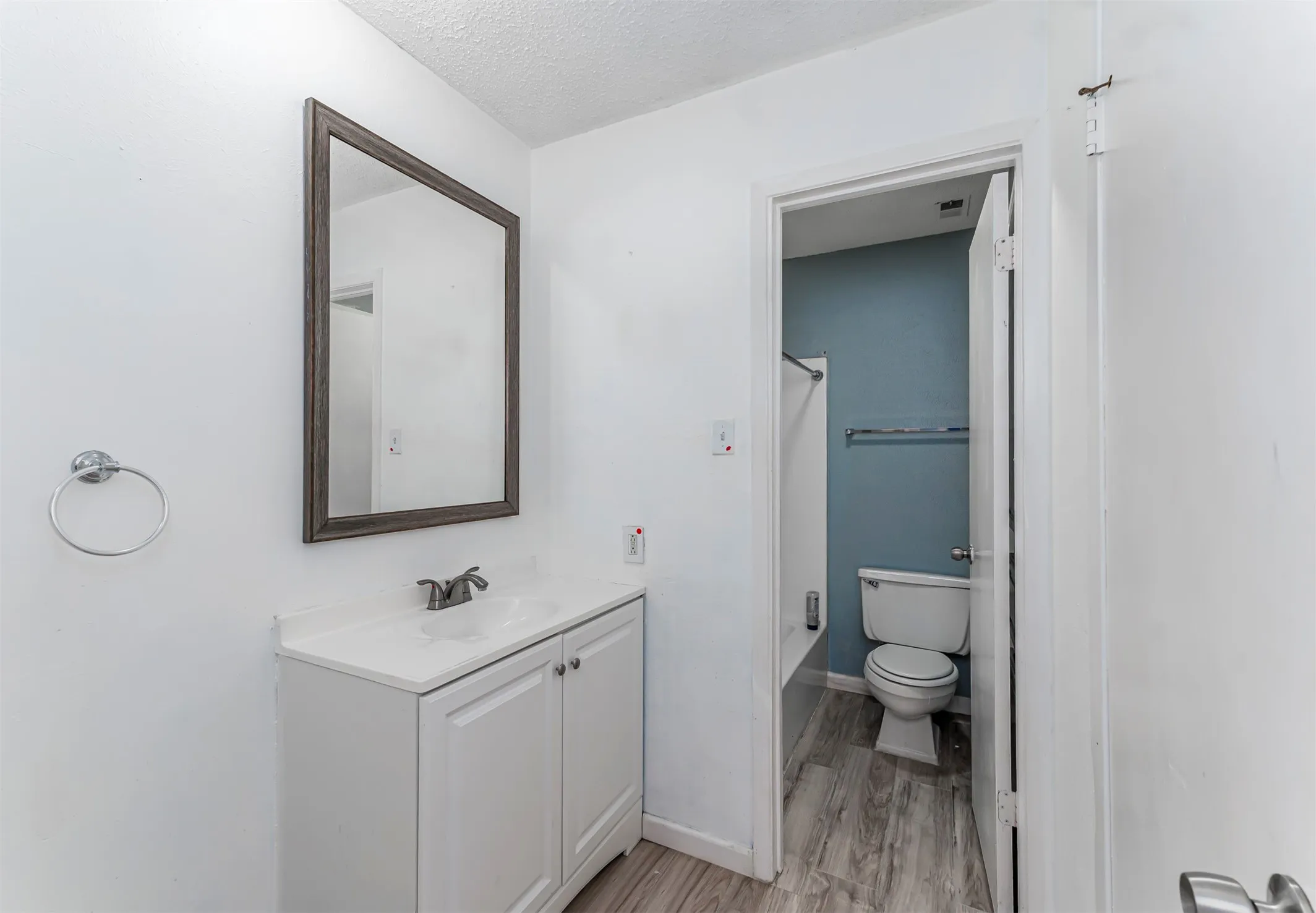 White vanity with integrated sink, chrome-finish faucet, and framed mirror