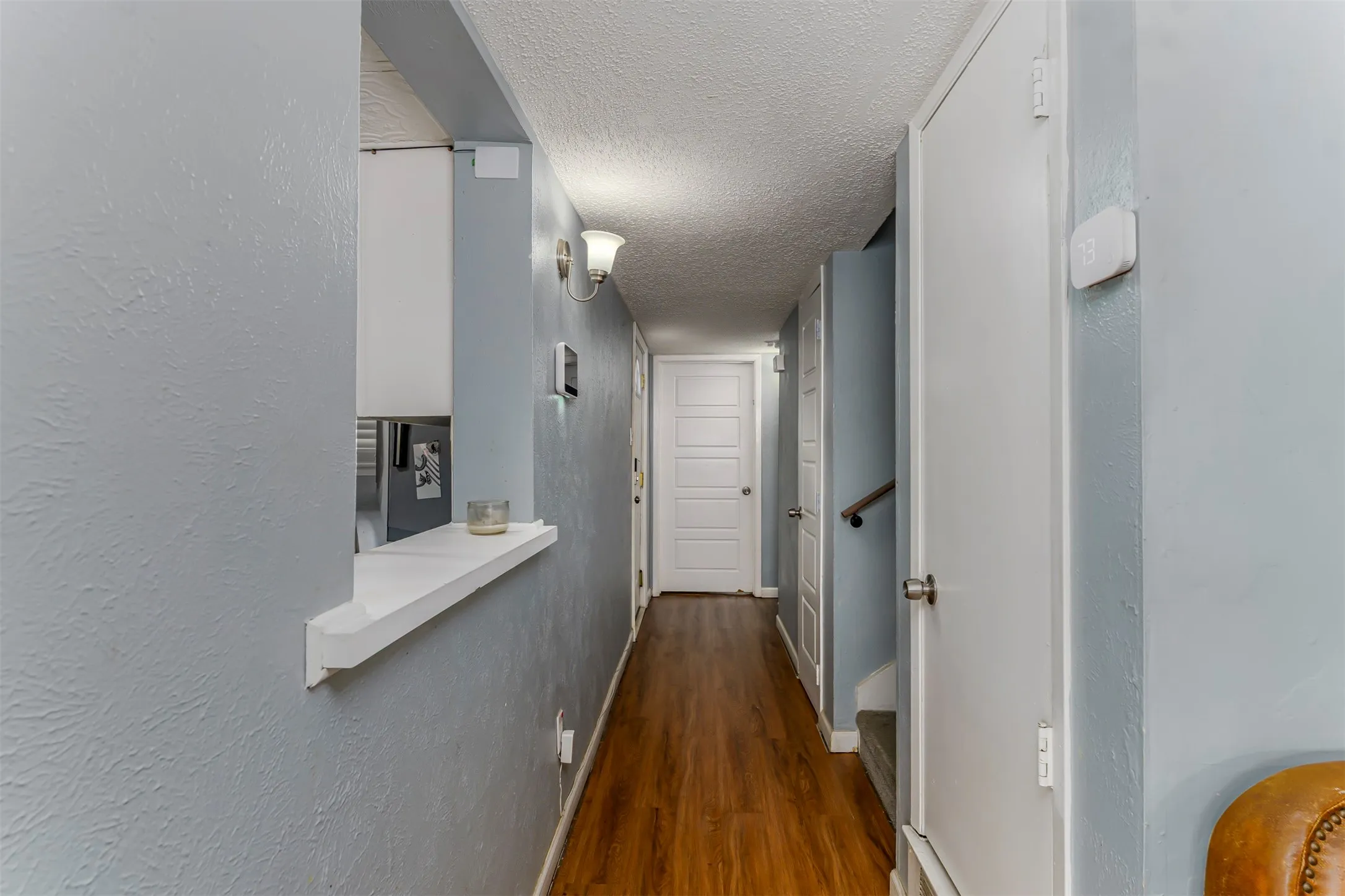 Wood-finish flooring throughout, white interior doors, and a built-in pass-through shelf