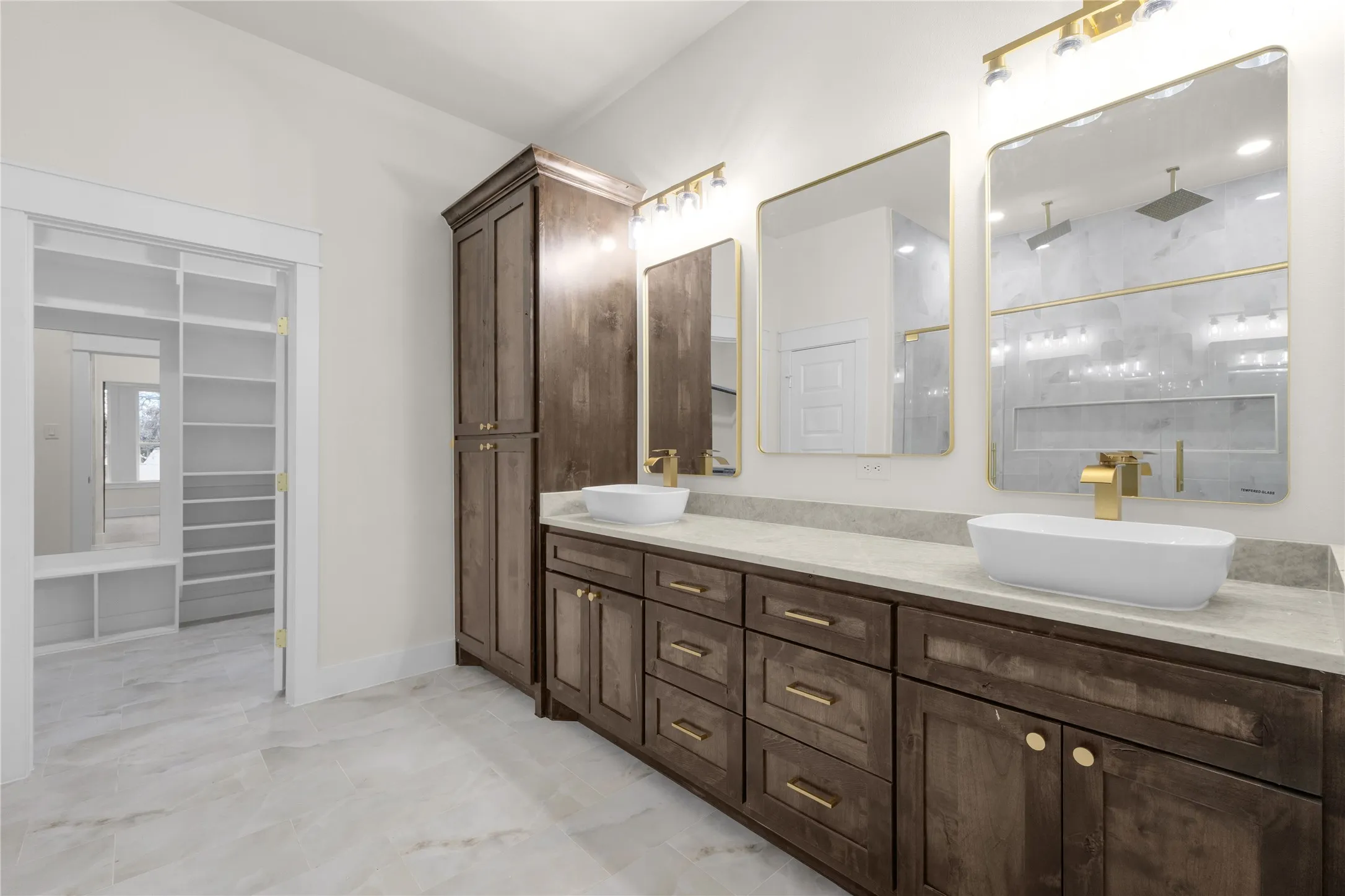 Dual vanity with vessel sinks, gold-finish fixtures, and framed mirrors