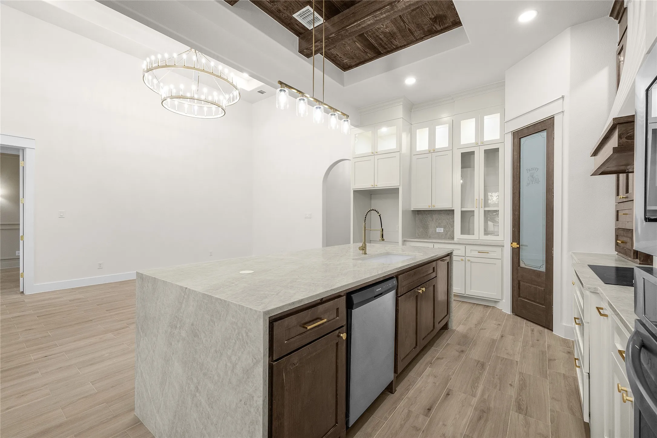 Kitchen island with a waterfall countertop, integrated sink, and dishwasher