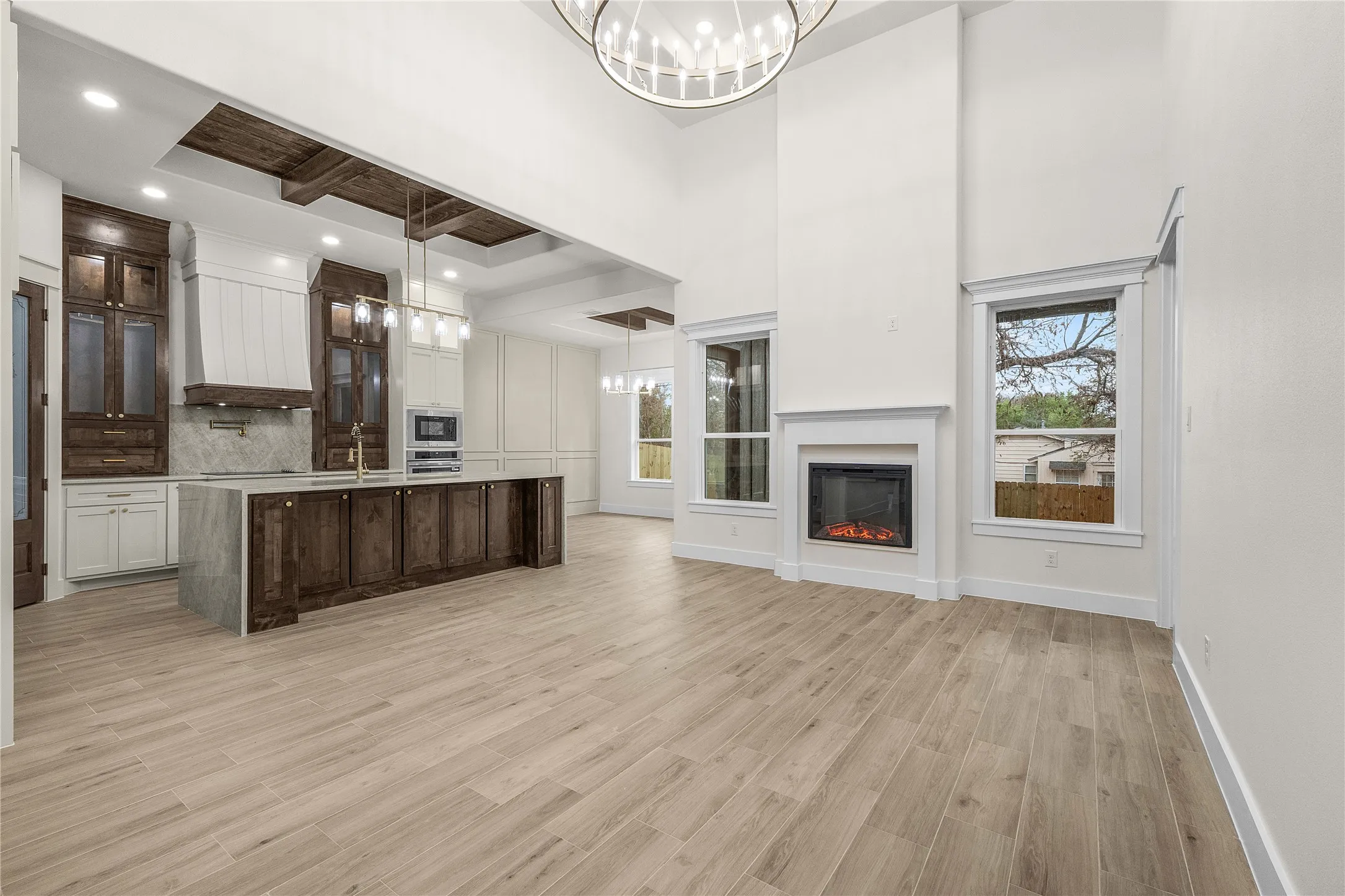 Vaulted ceilings, wood-finish flooring, and a fireplace with a white mantel