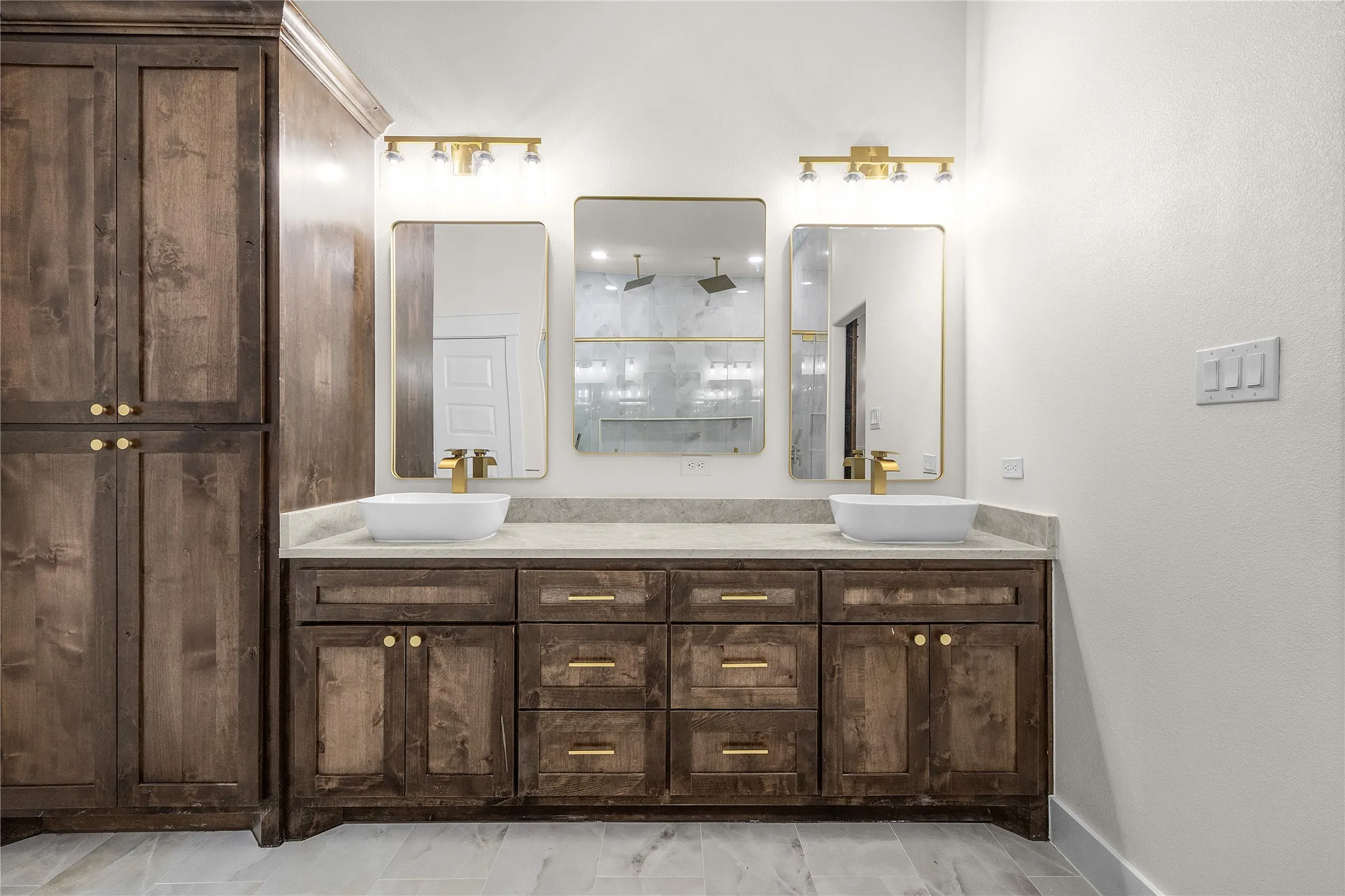 Dual vanity with light-toned countertop, two vessel sinks, and gold-finish fixtures
