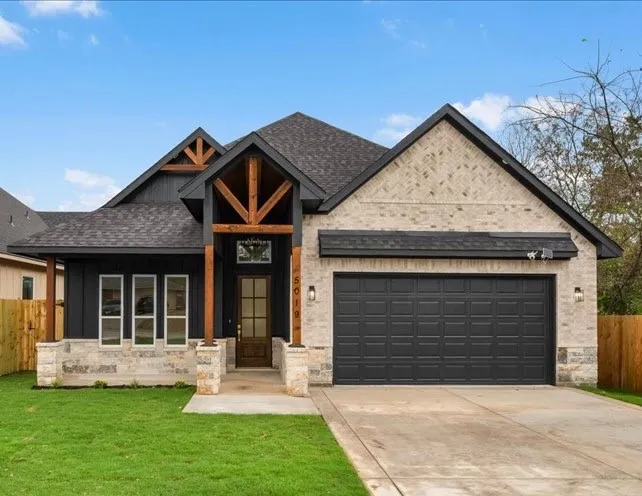 Stone and brick facade with wood beam accents, dark shingle roof, and a two-car garage