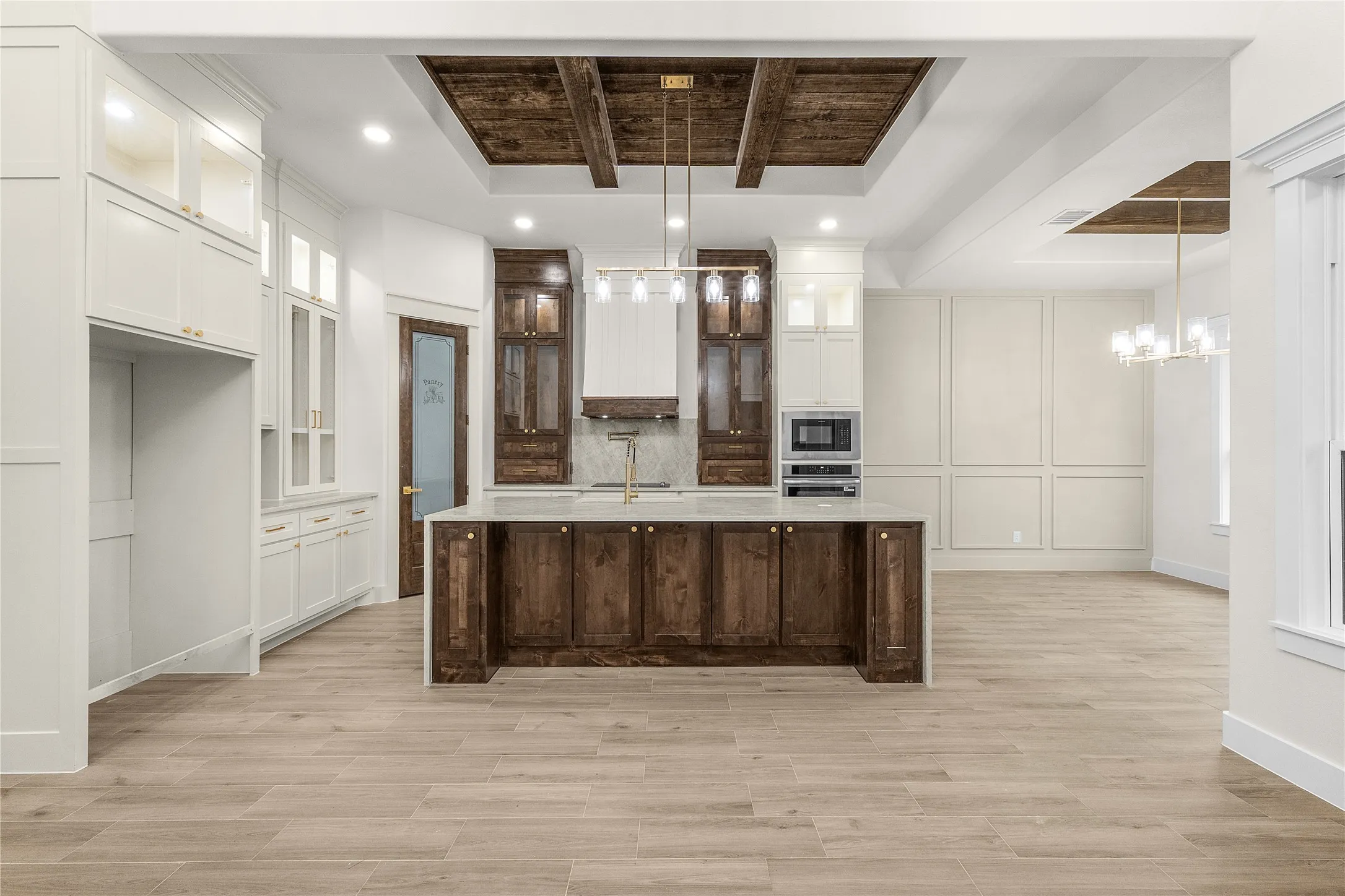 Spacious kitchen featuring a large island, wood-finish flooring, and a coffered ceiling with wood accents