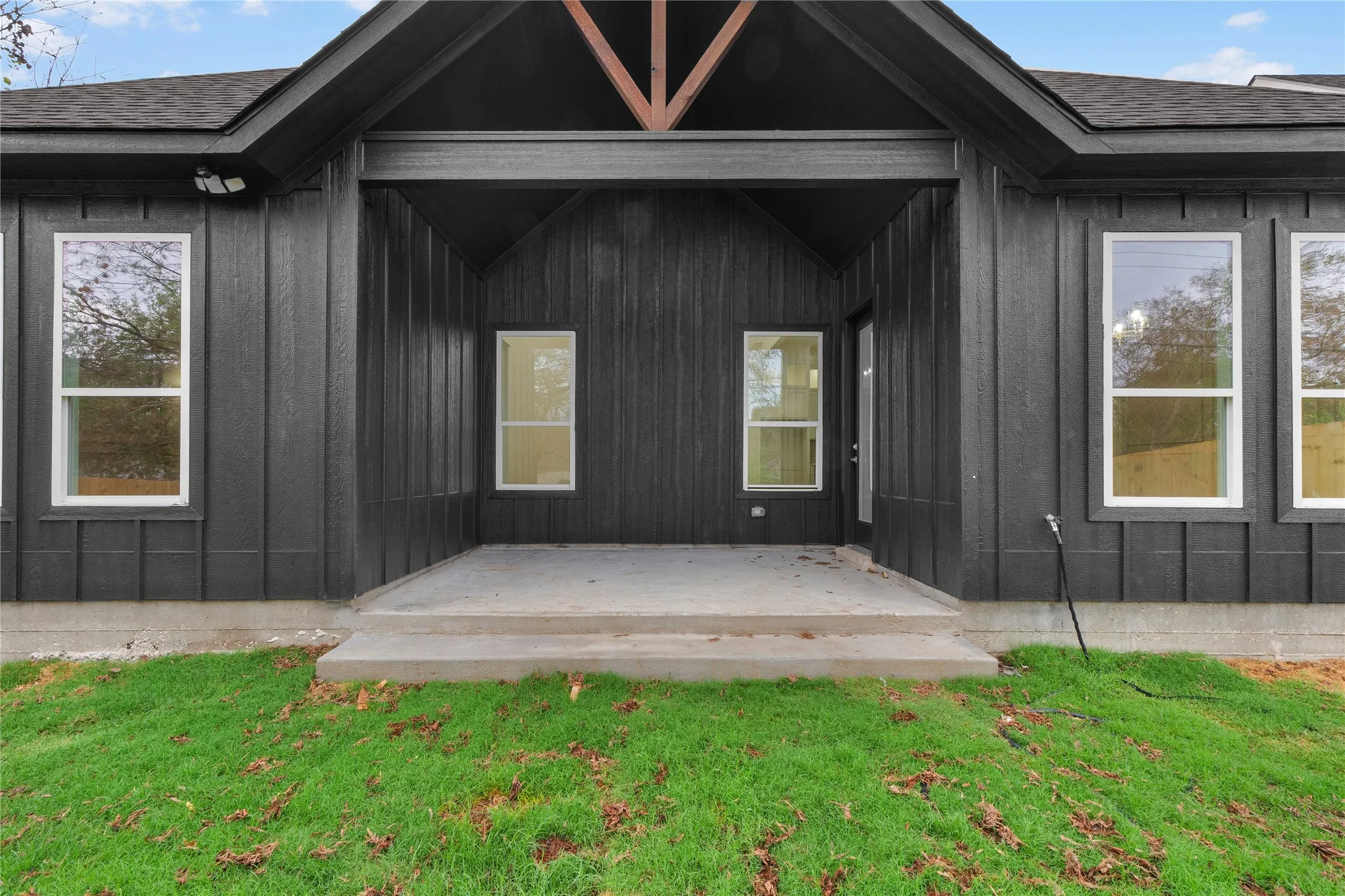 Board-and-batten siding with a covered concrete patio and exposed wood rafter tails