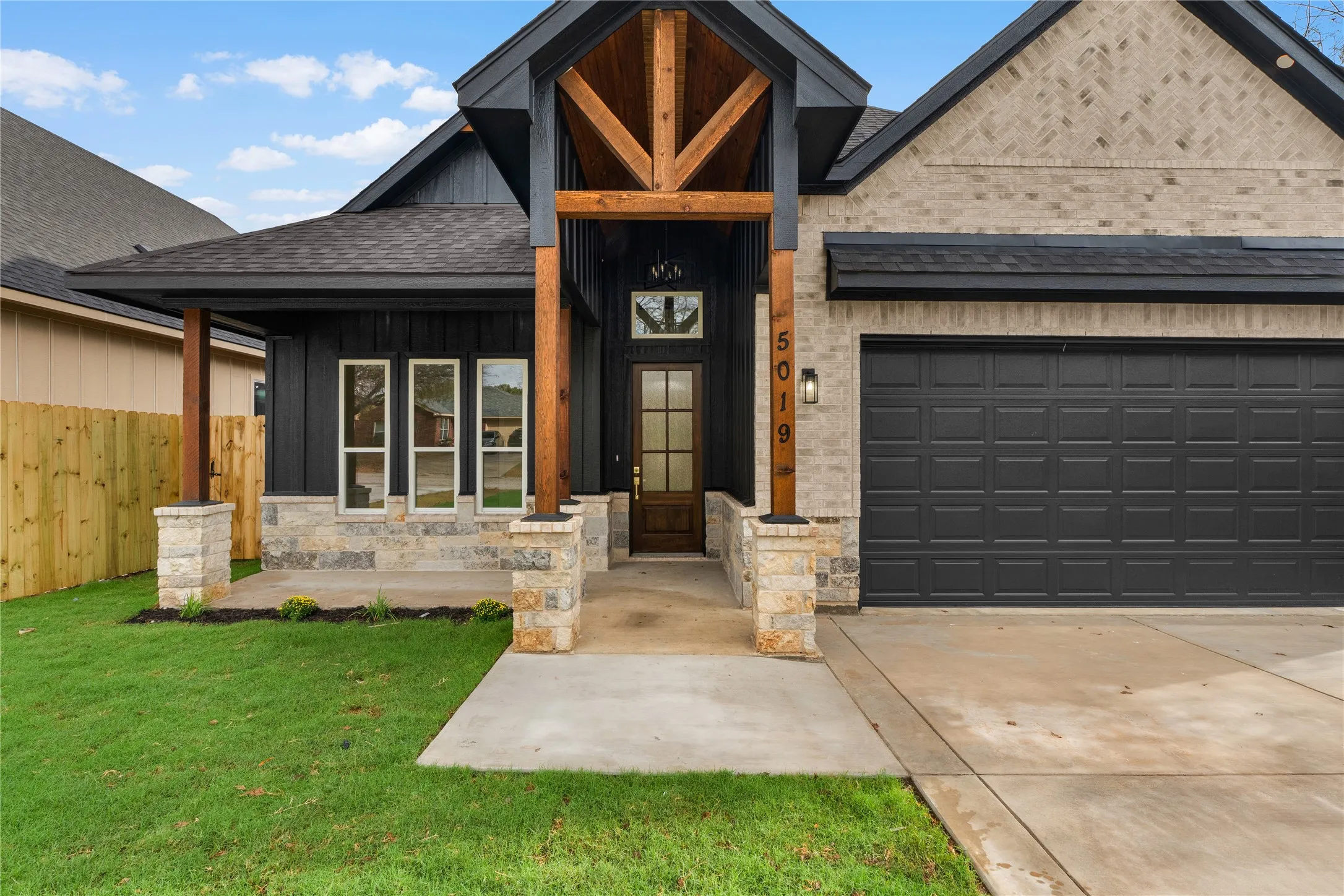 Modern farmhouse-inspired exterior with board-and-batten siding, light-colored brick, and stone accents