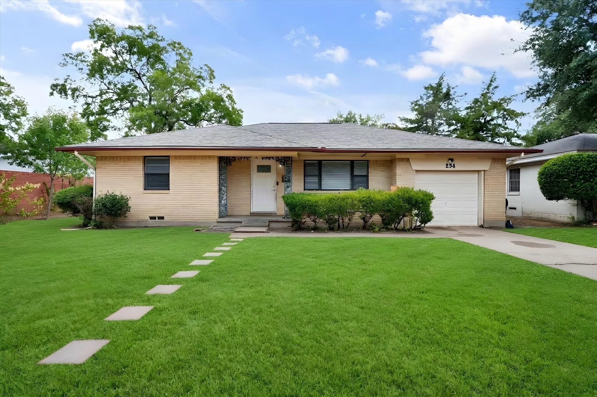 Brick exterior with a single-car garage, concrete driveway, and a stepping stone pathway