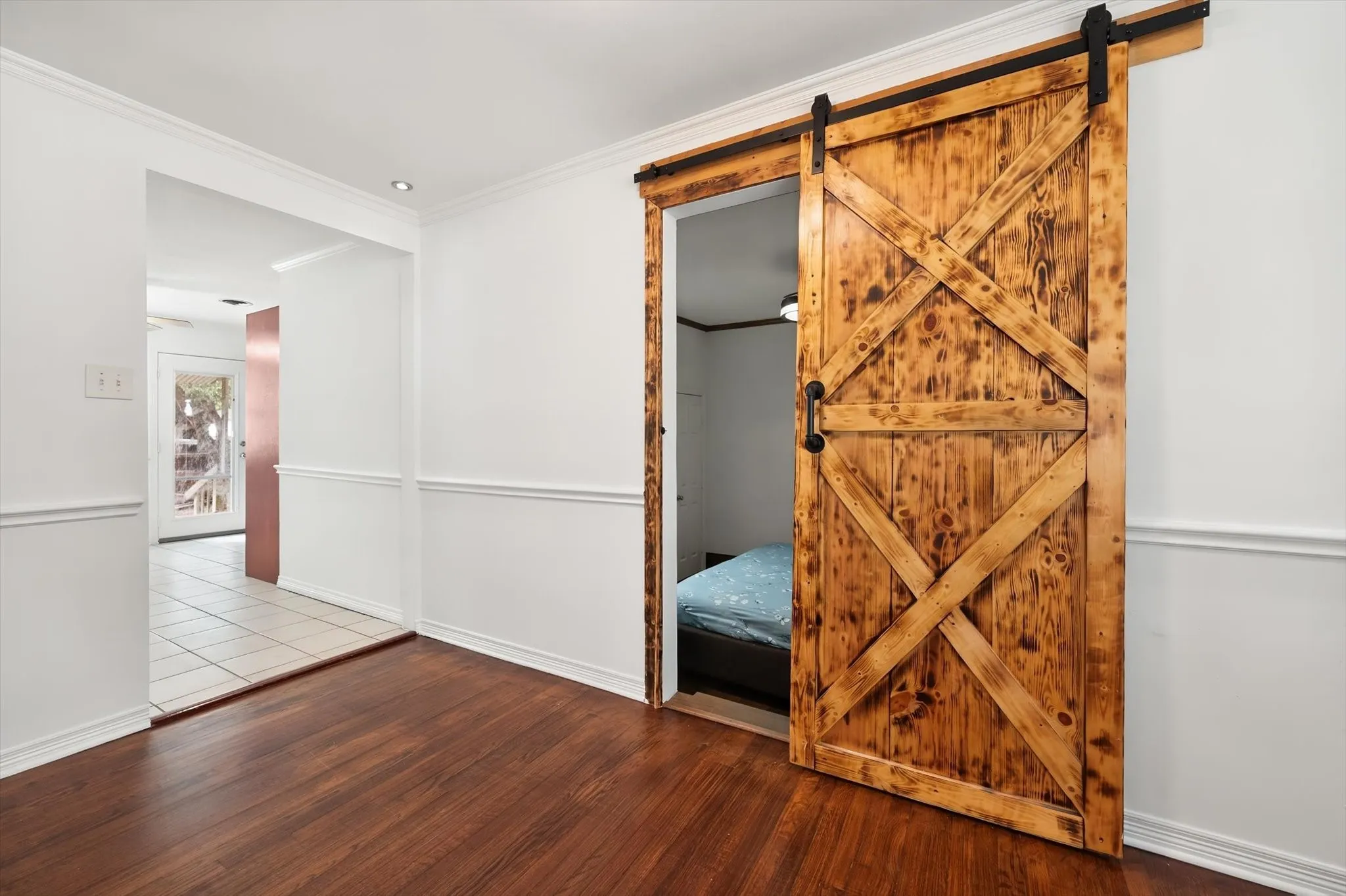 Wood-finish flooring with a rustic barn door featuring black hardware