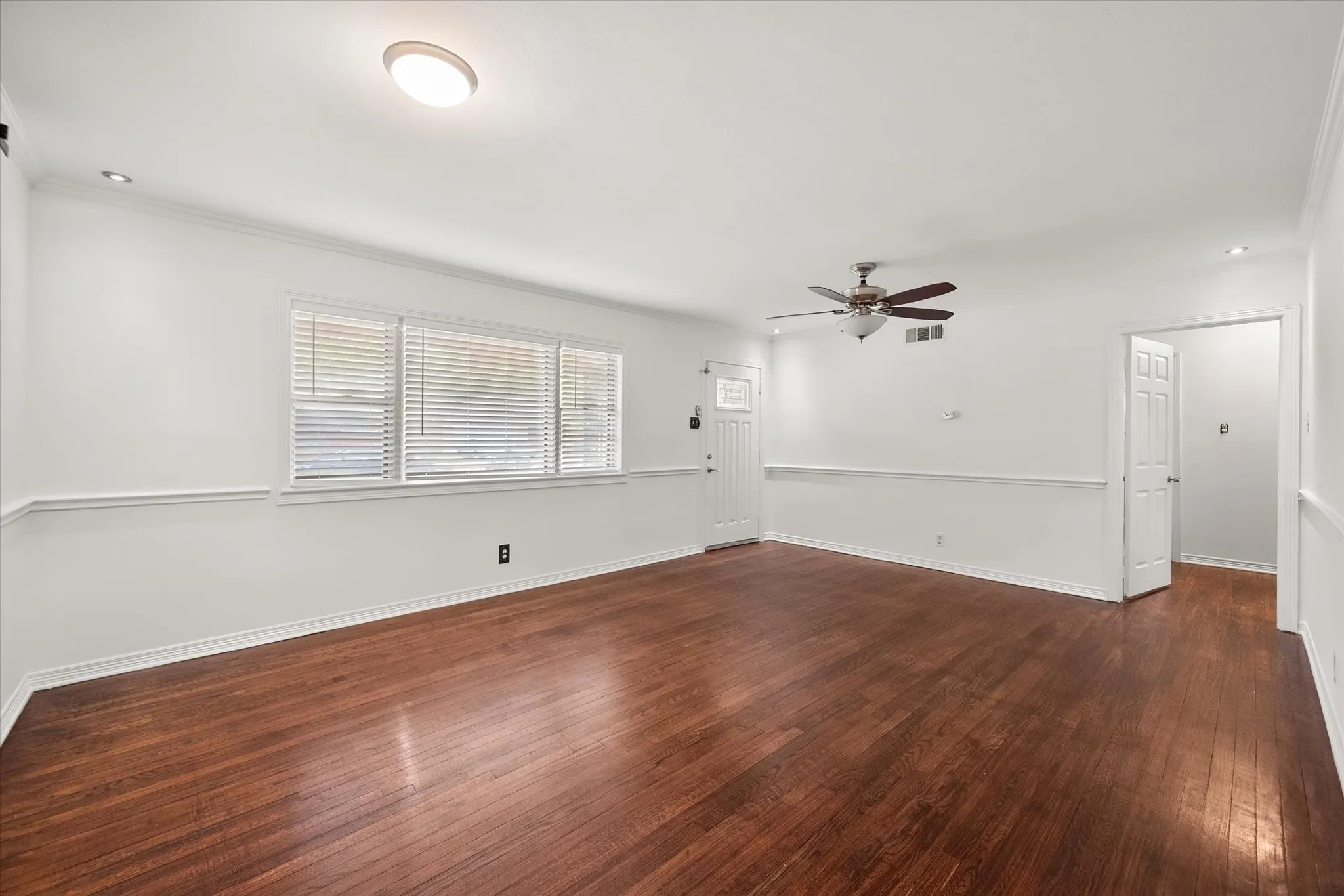 Wood-finish flooring, recessed lighting, ceiling fan, and white doors