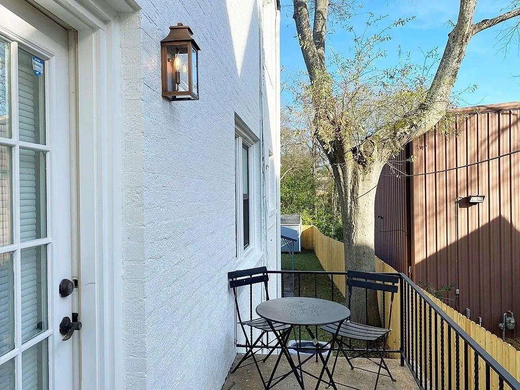 Private balcony with iron railing, exterior wall lantern, and a wood privacy fence
