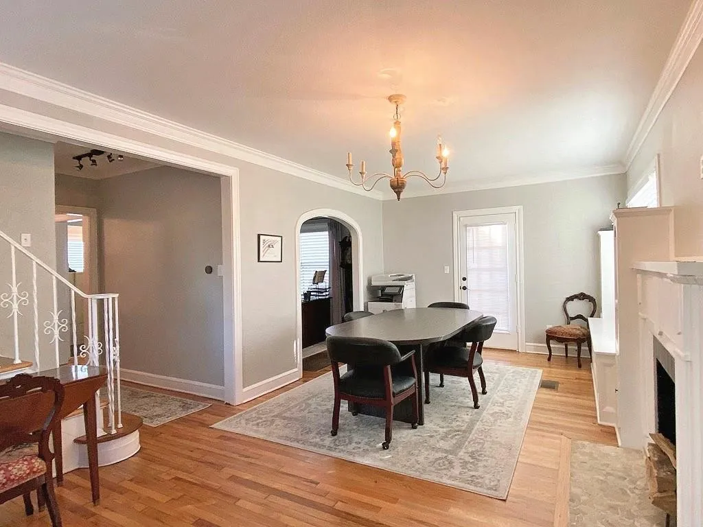 Hardwood flooring, crown molding, built-in fireplace, arched entryway, and a candelabra-style chandelier