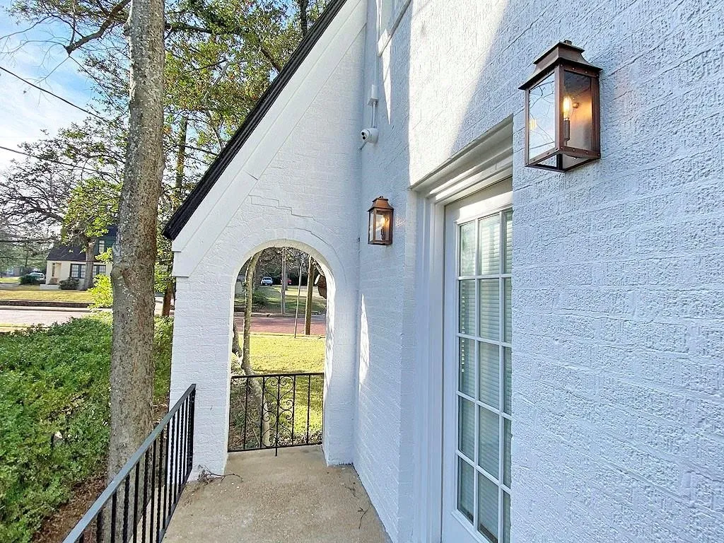 Textured white brick exterior with a black pitched roofline, arched entryway, and black metal railings