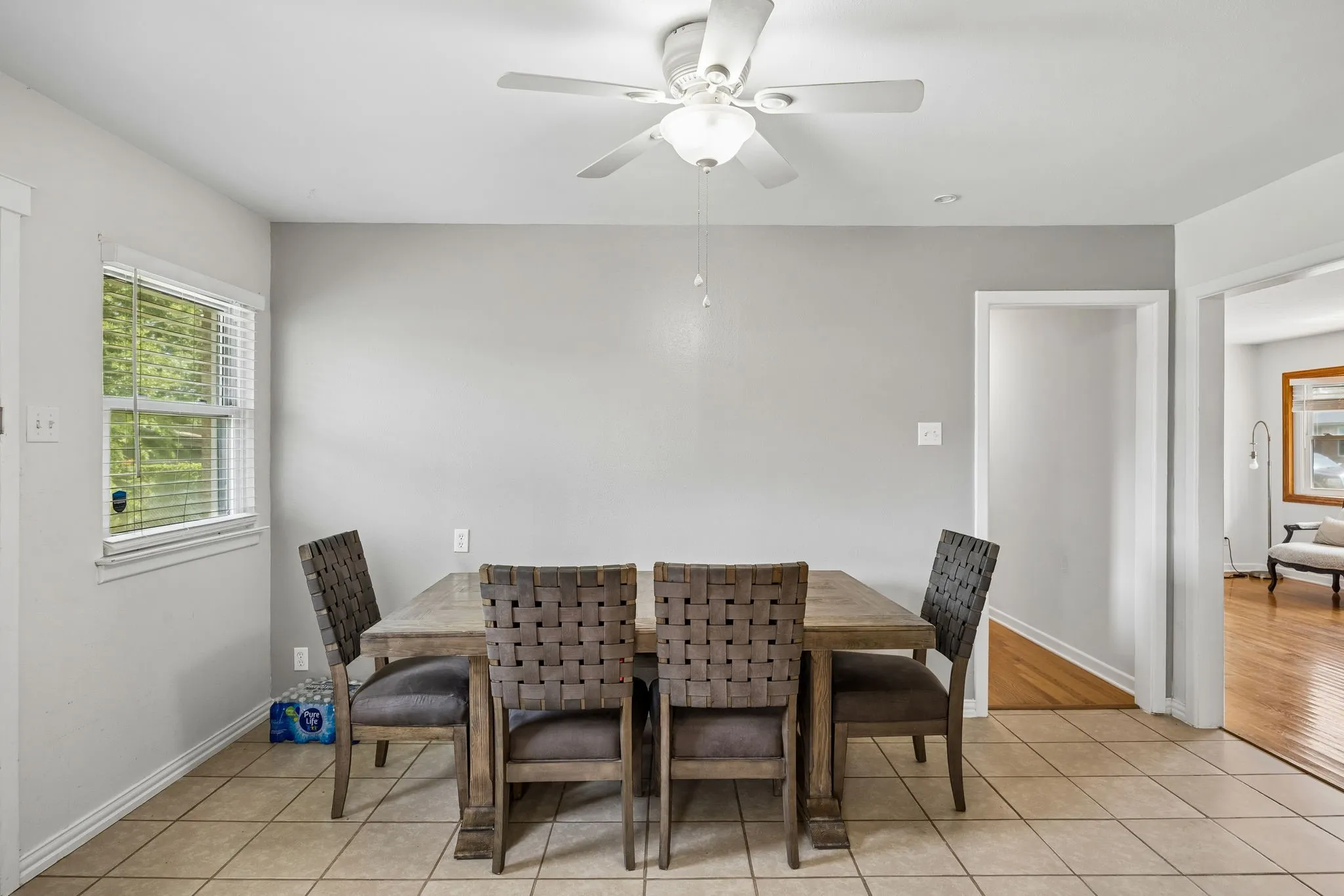 Tile flooring, window with blinds, ceiling fan with light fixture, light gray wall color, white trim