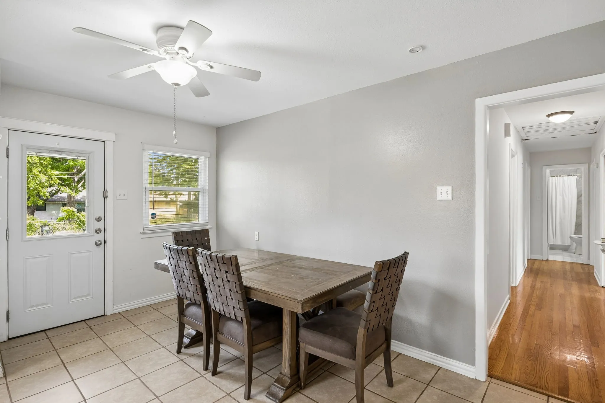Ceramic tile flooring, white ceiling fan with integrated lighting, recessed lighting, white panel door with glass insert, wood-finish flooring in hallway