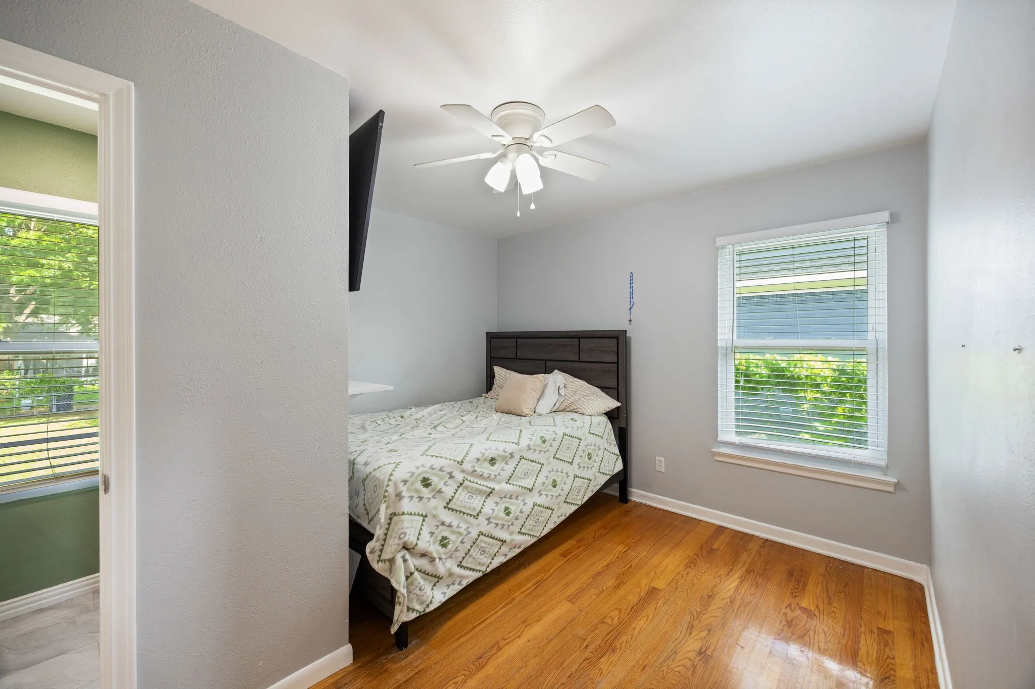Hardwood flooring, ceiling fan, natural light, window blinds, and light gray wall paint