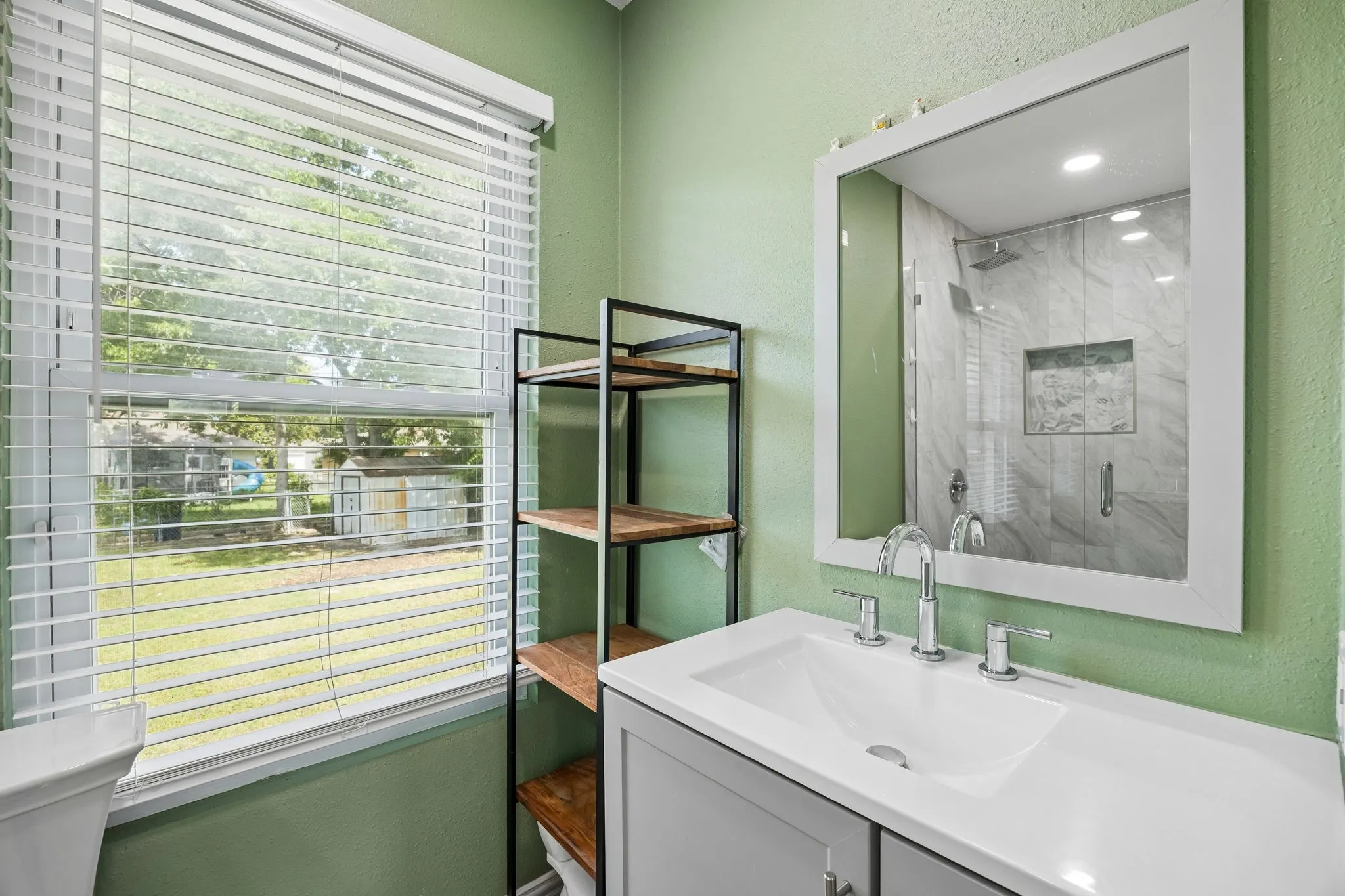 Bathroom featuring a vanity with an integrated sink, polished chrome faucet, and framed mirror