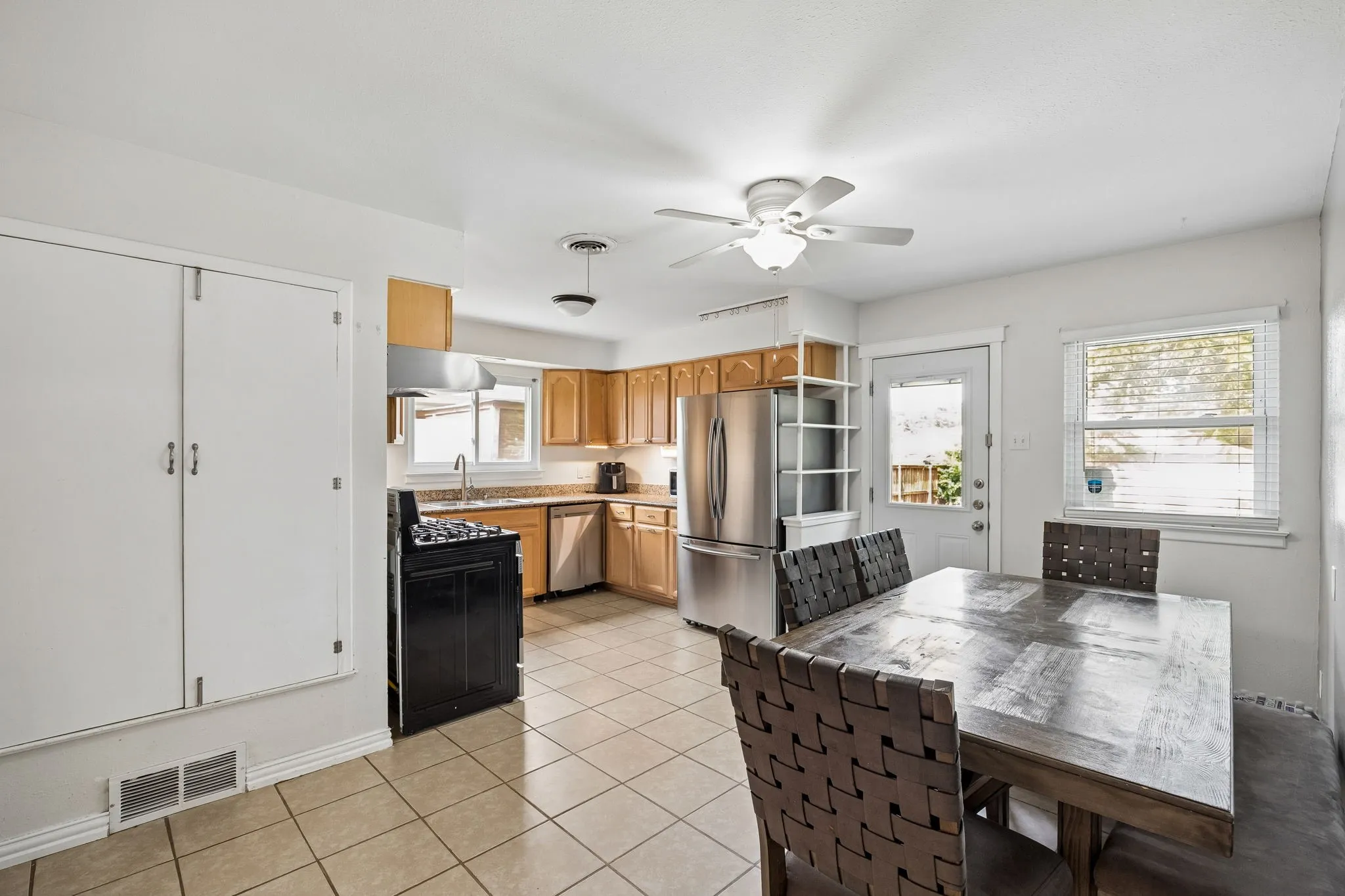 Kitchen featuring tile flooring, wood cabinetry, stainless steel appliances, and a ceiling fan