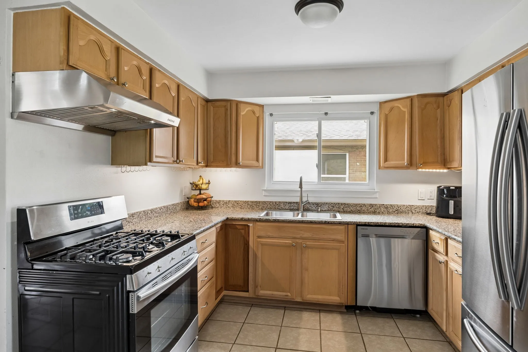 Kitchen featuring wood cabinetry, light-toned countertops, and stainless steel appliances
