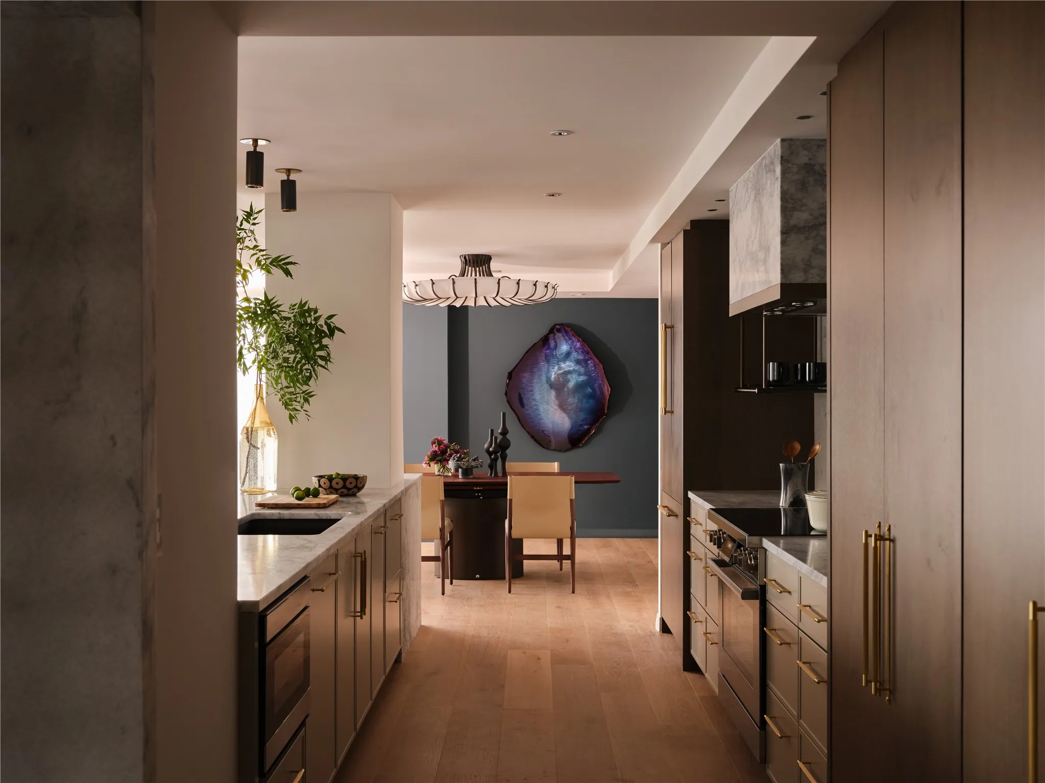Kitchen leads to dining room with feature wall and Arteriors lighting.