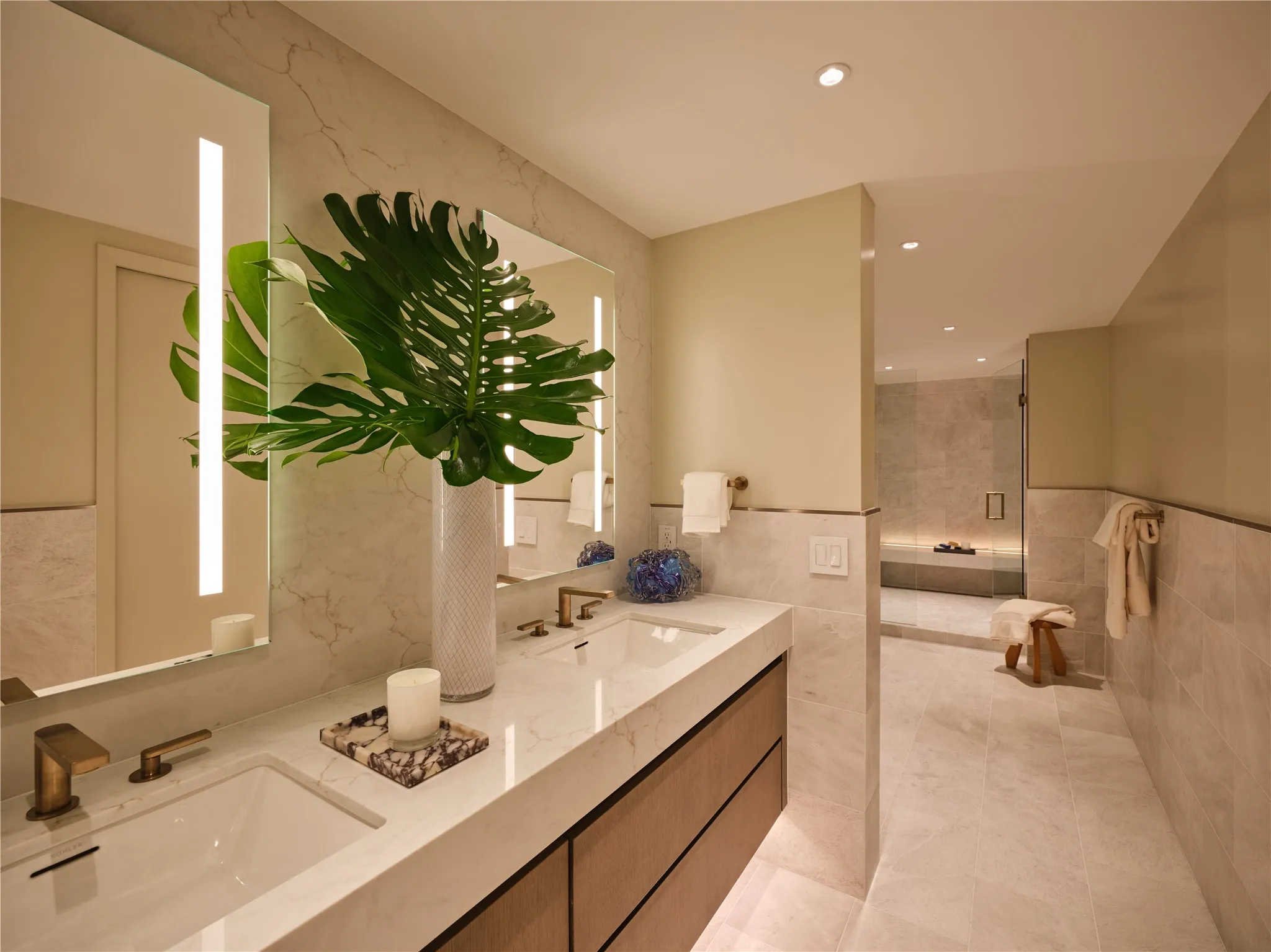 Primary bath with Iceberg honed-marble floors and wainscoting. Large shower has a floating bench with built-in LED lighting. Adjoining custom walk-in closet.