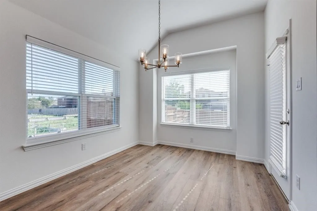 Vaulted ceiling, wood-finish flooring, contemporary chandelier, multiple windows, white baseboards