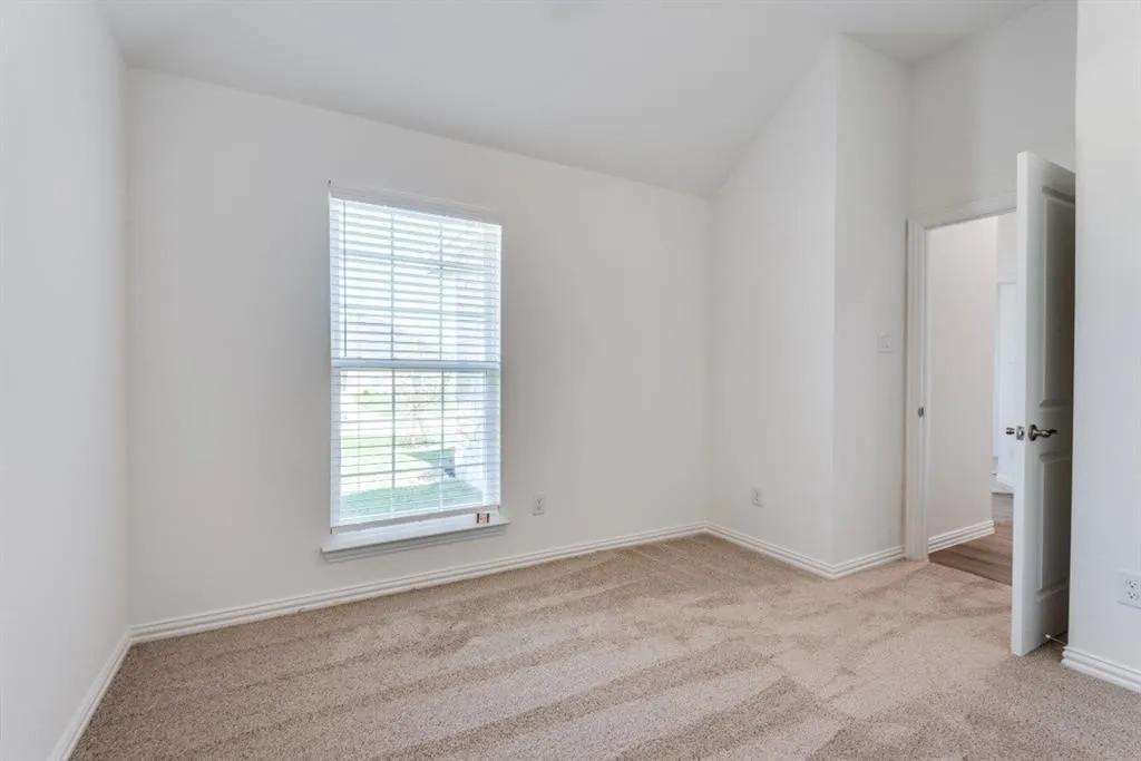 Carpeted flooring, vaulted ceiling, white interior paint, single window, white window blinds