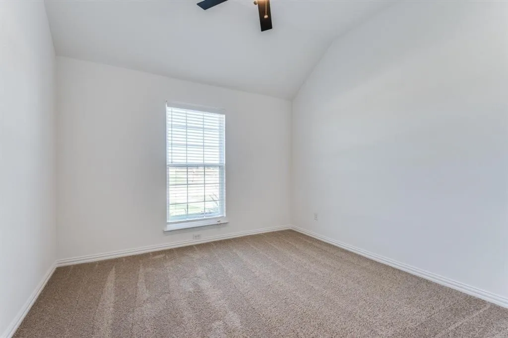 Vaulted ceiling, ceiling fan, single window with blinds, light-colored walls, and carpet flooring