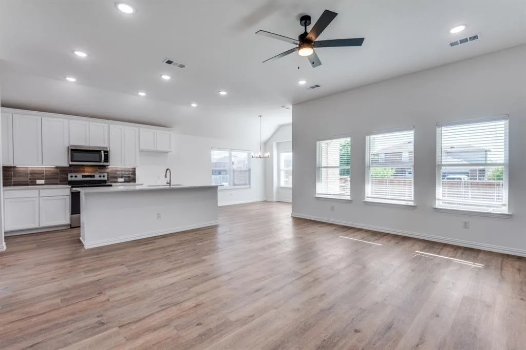Open-concept living area with wood-finish flooring, recessed lighting, and a ceiling fan