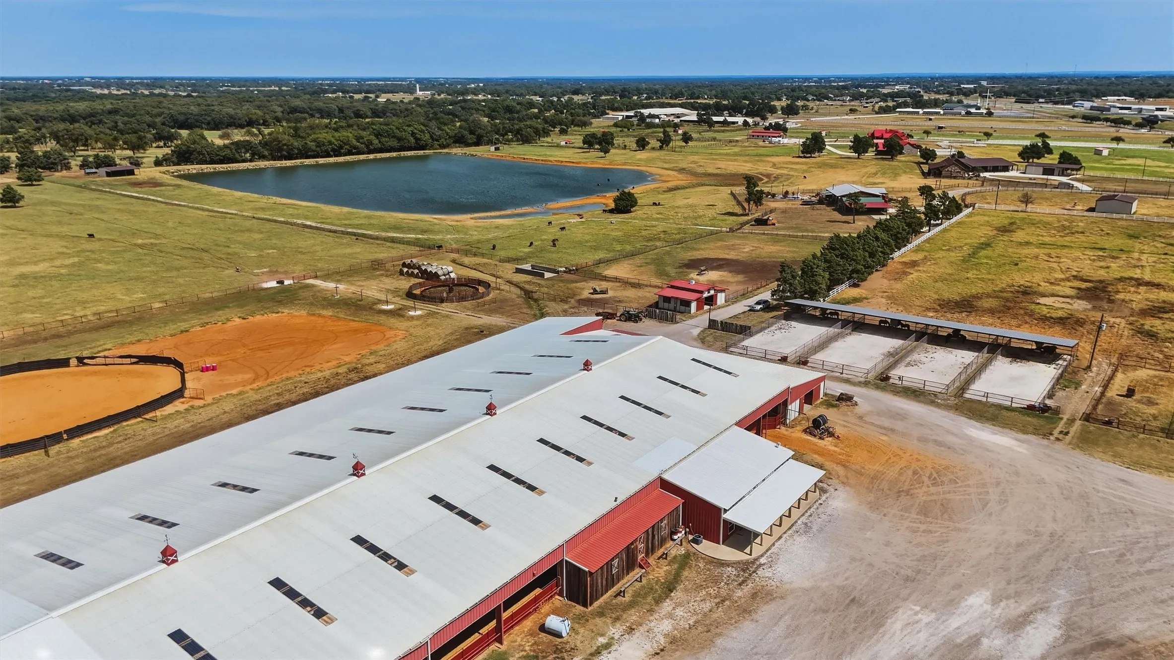 View of the 4 turn-out lots to the east of the covered arena, the 2-stall barn, and the round pen and horse walker behind the arena.