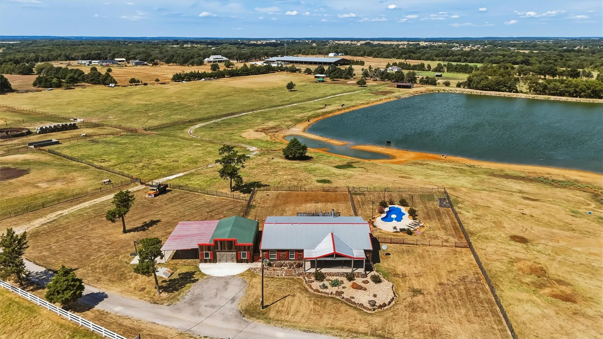 Aerial of Triple-wide mobile home with in-ground swimming pool and storm shelter - east of the covered arena on connecting driveway to adjacent related property.