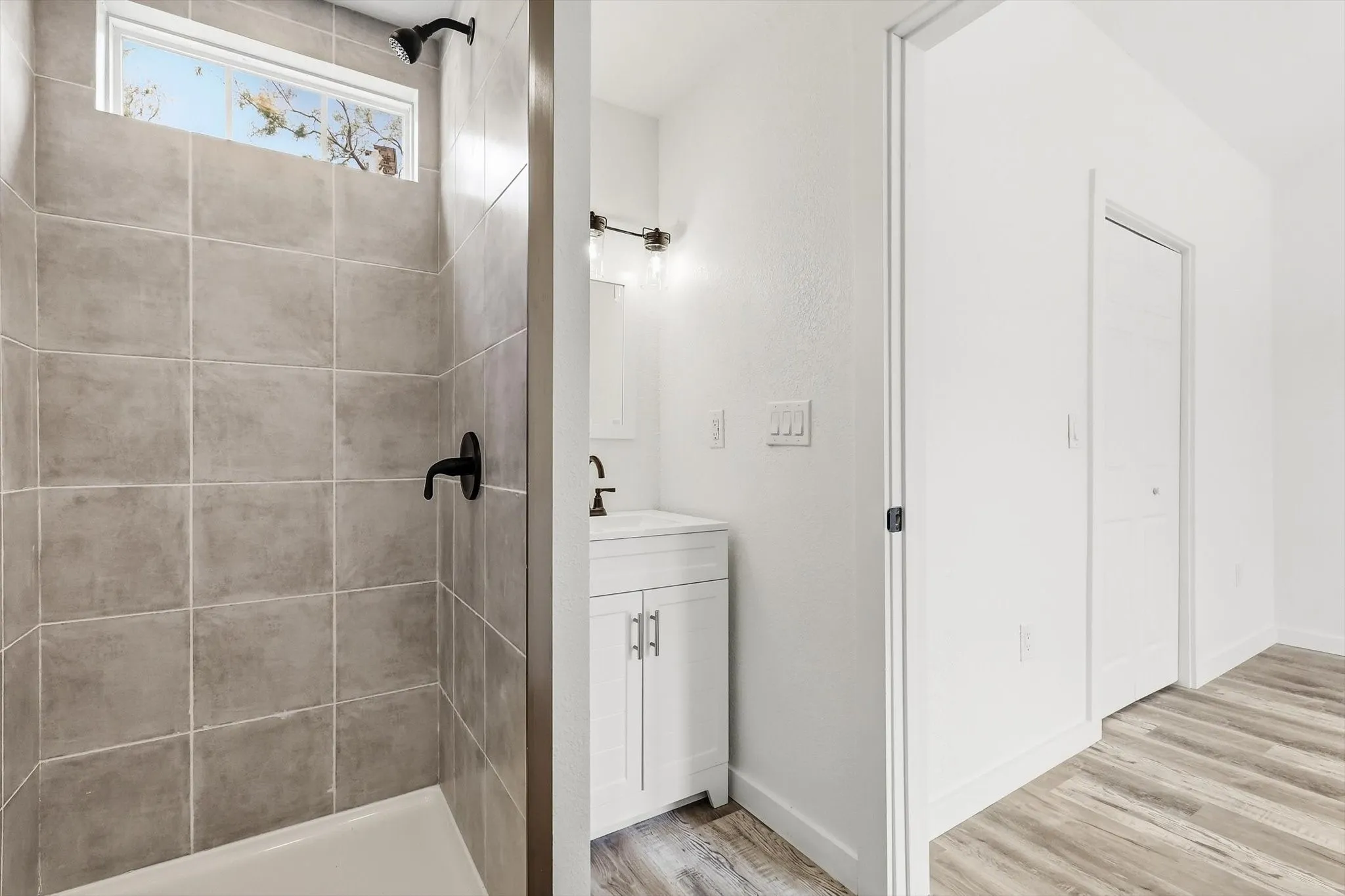 Tiled shower with matte black fixtures and transom window