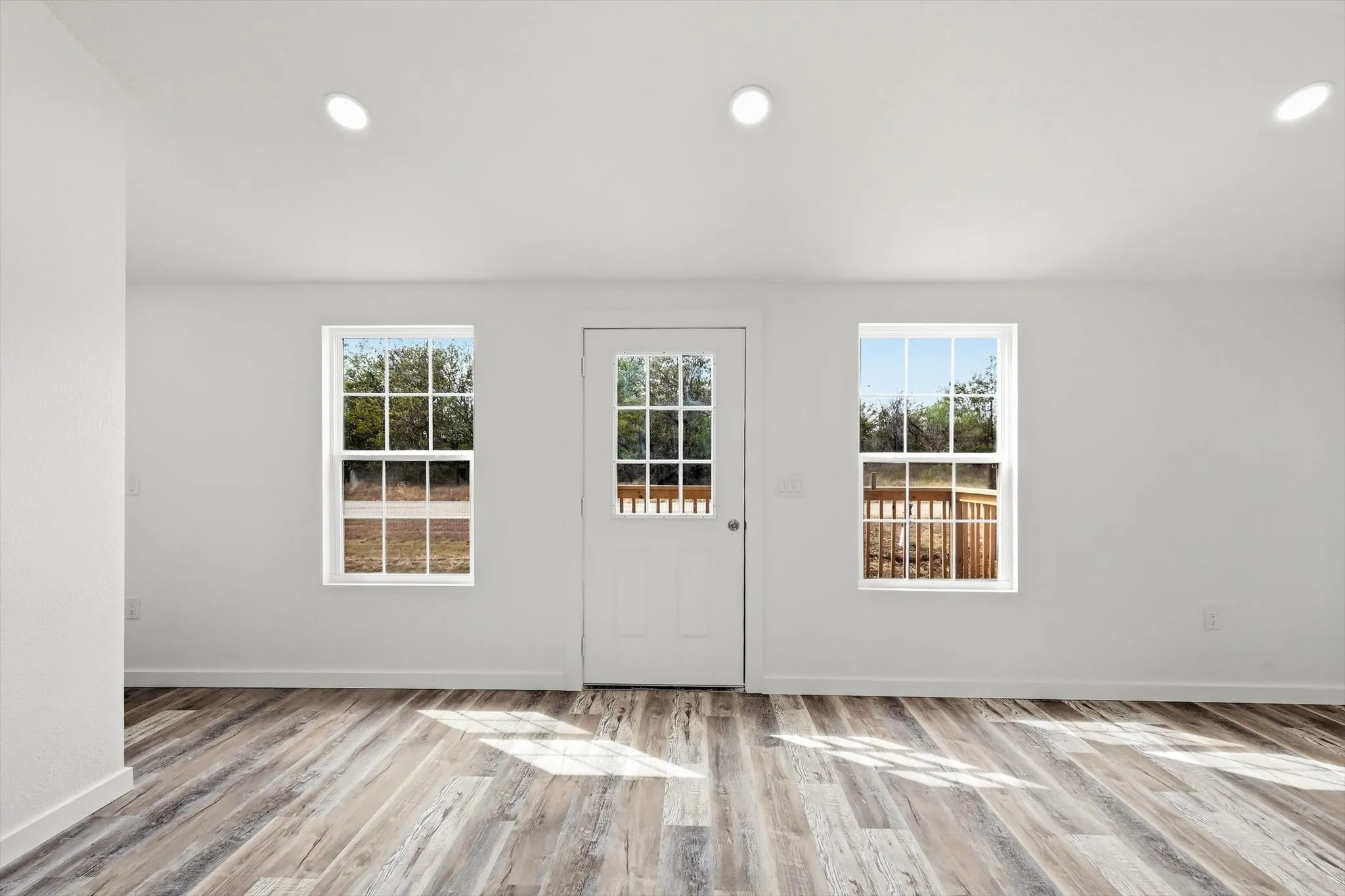 Wood-finish flooring, recessed lighting, white walls, and a white door with integrated window panels