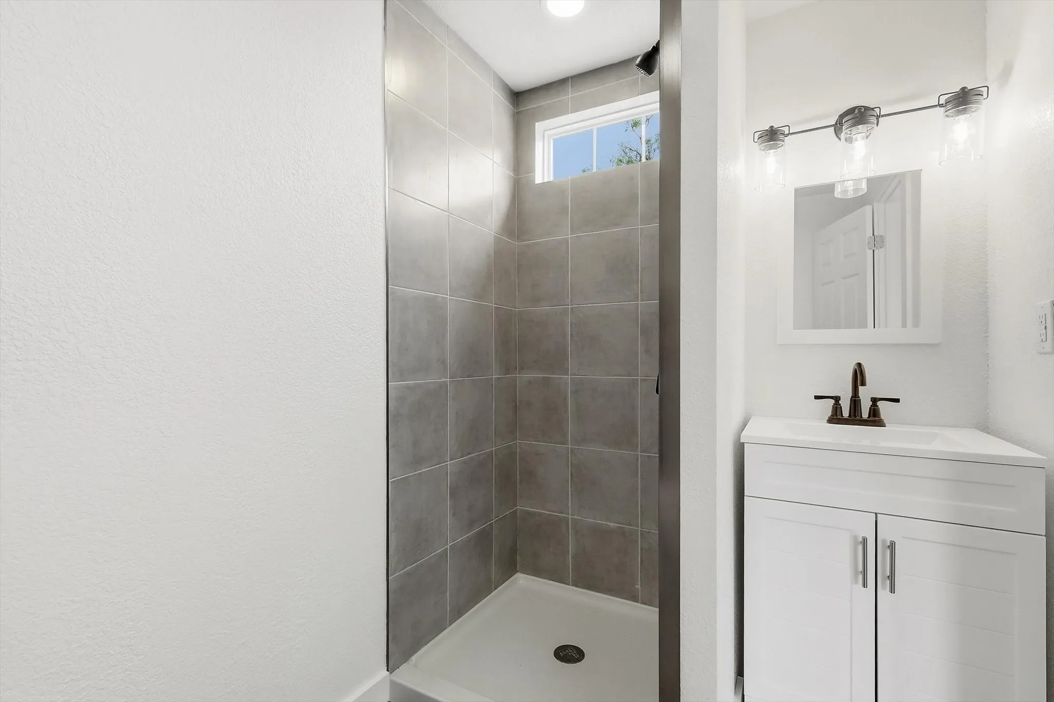 Shower with grey tiled walls and a window