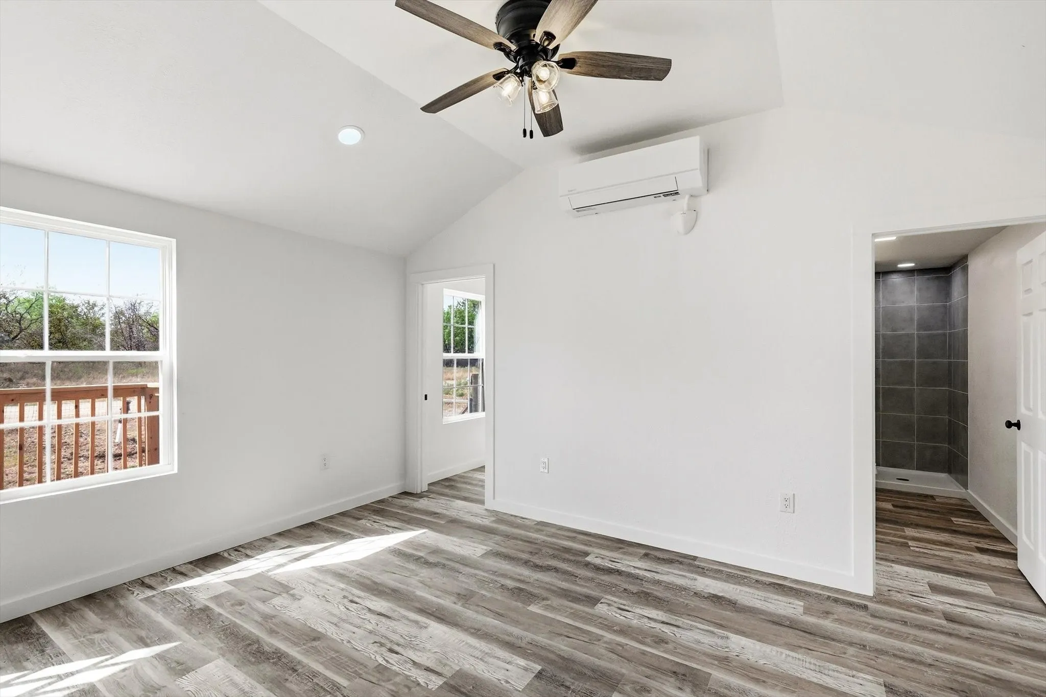 Vaulted ceiling with a ceiling fan, recessed lighting, wood-finish flooring, and a mini-split air conditioning unit