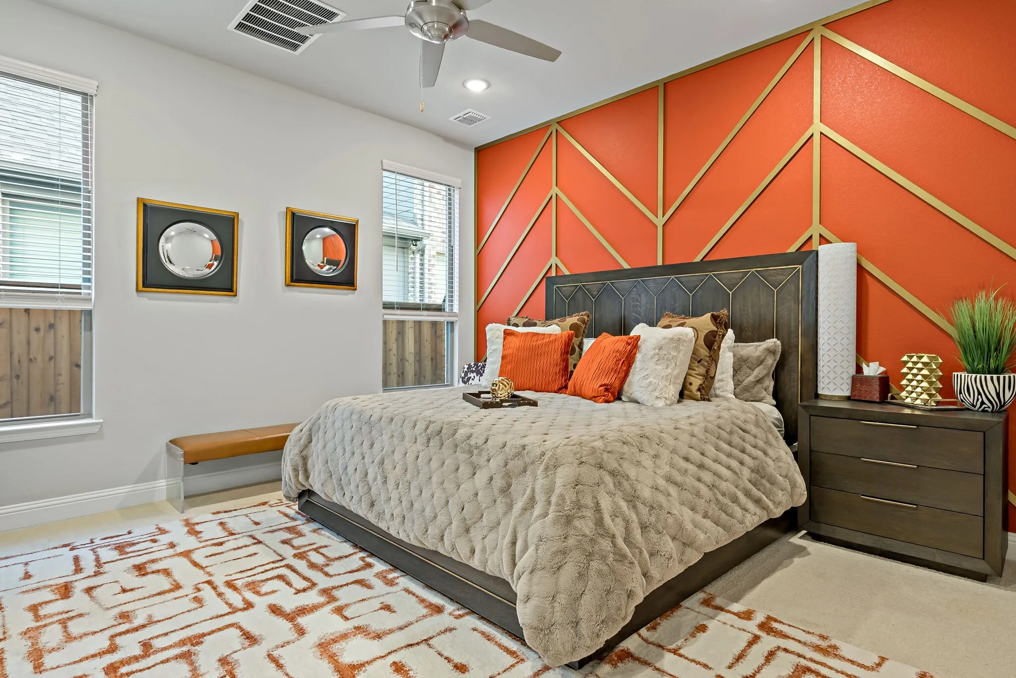 Bedroom featuring a decorative accent wall with geometric gold detailing on an orange background