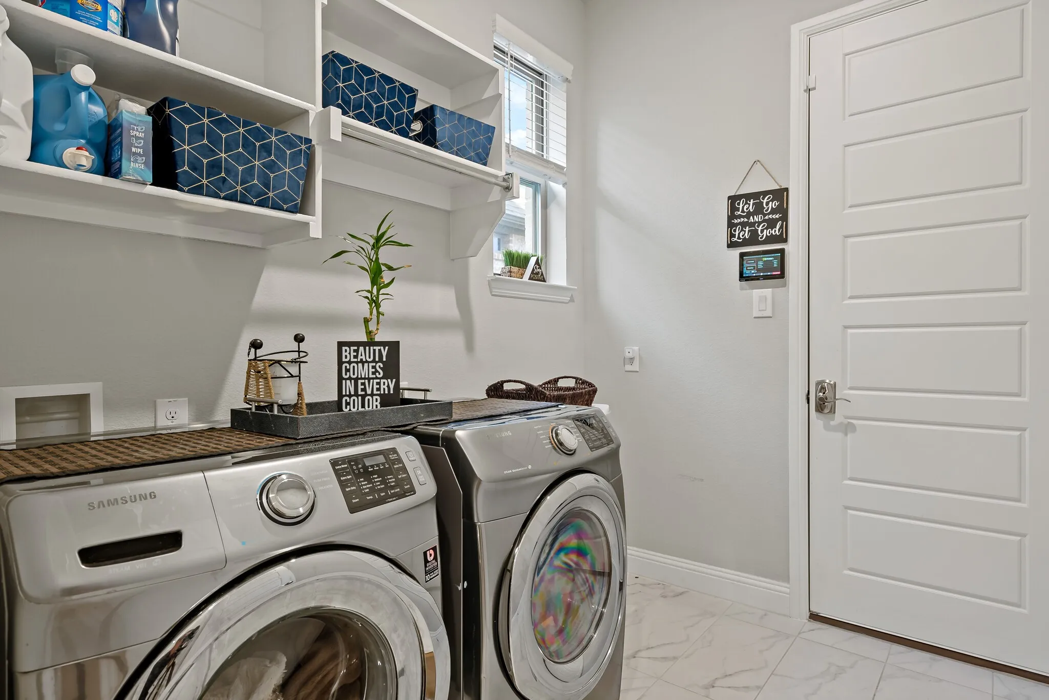 Dedicated laundry area featuring white wall shelving, a window with blinds, and white panel doors