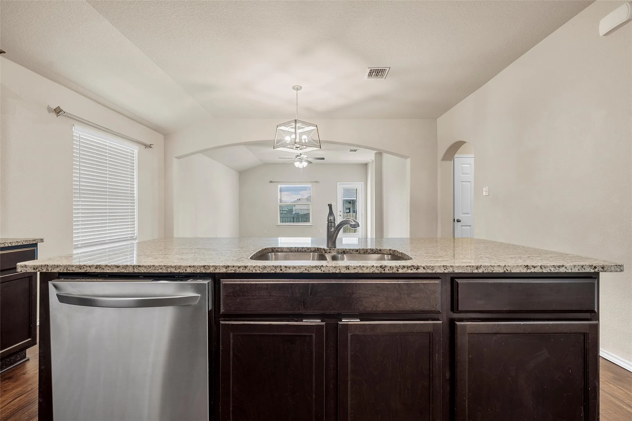 Kitchen featuring dishwasher, ceiling fan, dark wood-style floors, arched walkways, and dark brown cabinetry