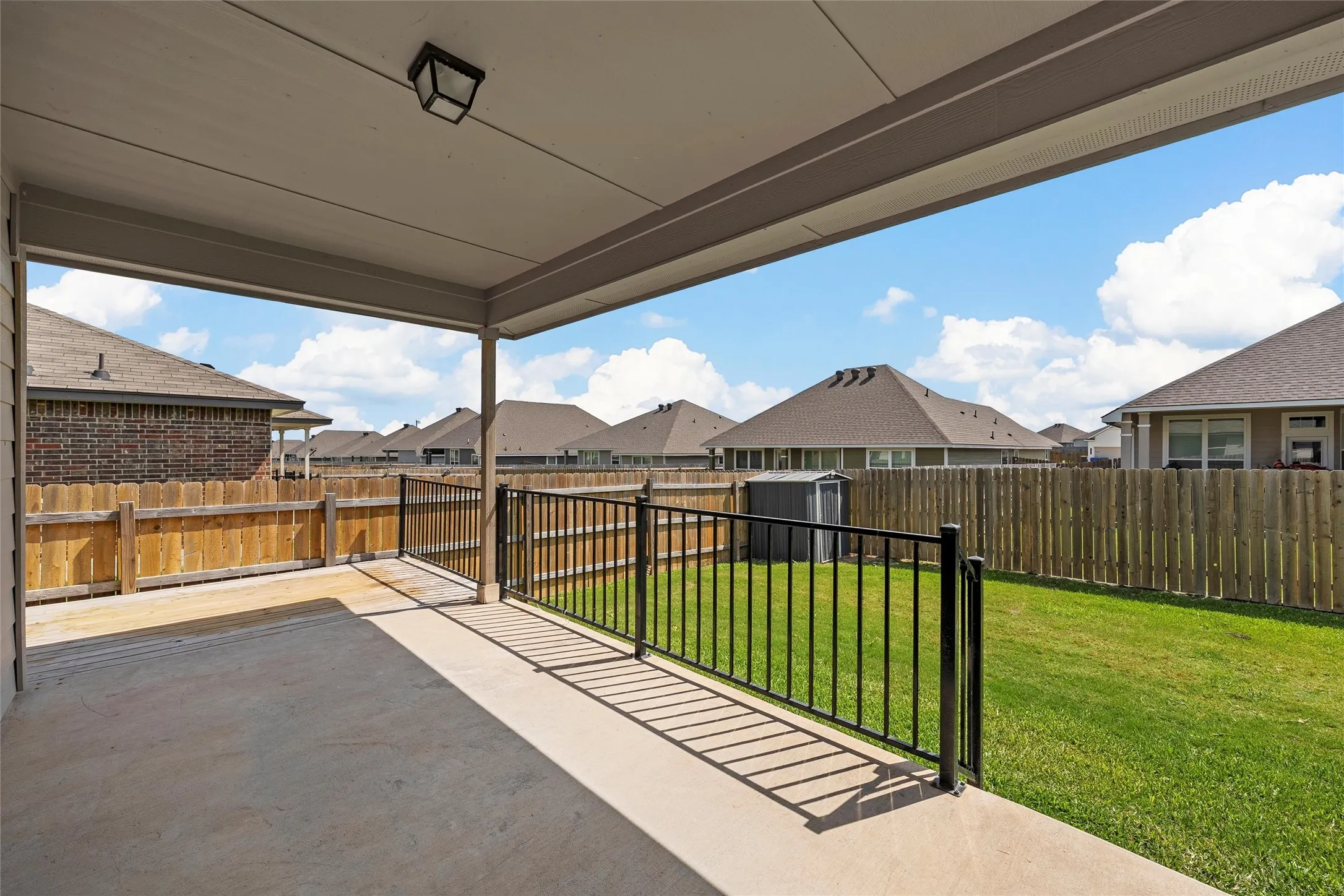 Fenced backyard with a patio, a shed, and a residential view
