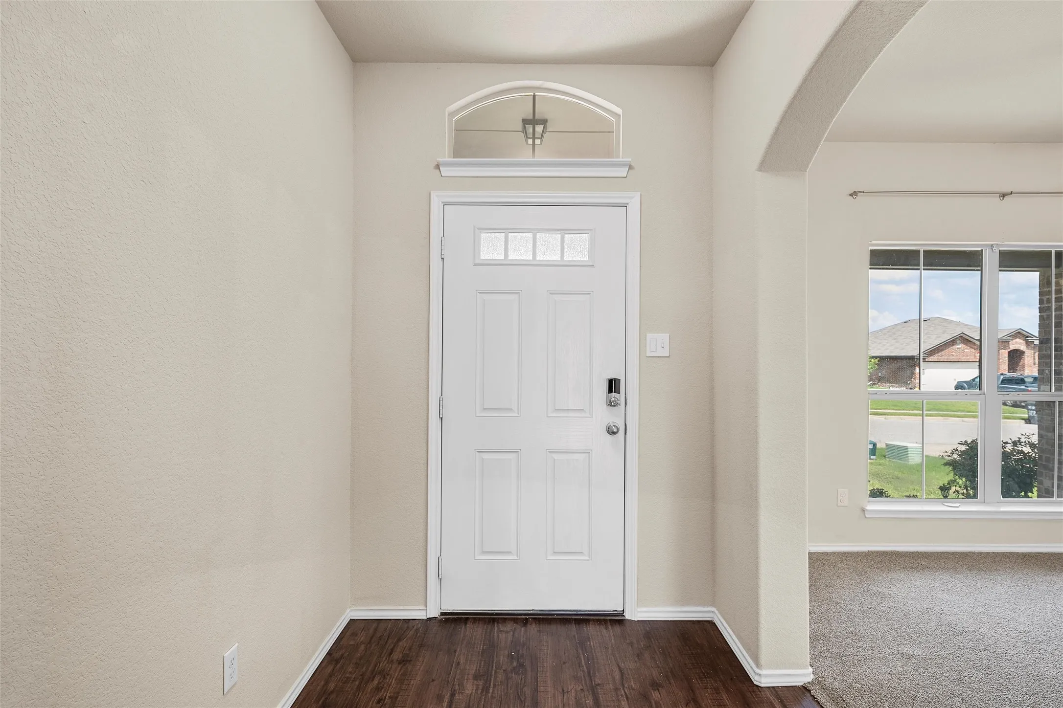 Foyer featuring arched walkways, healthy amount of natural light, and dark wood-style flooring