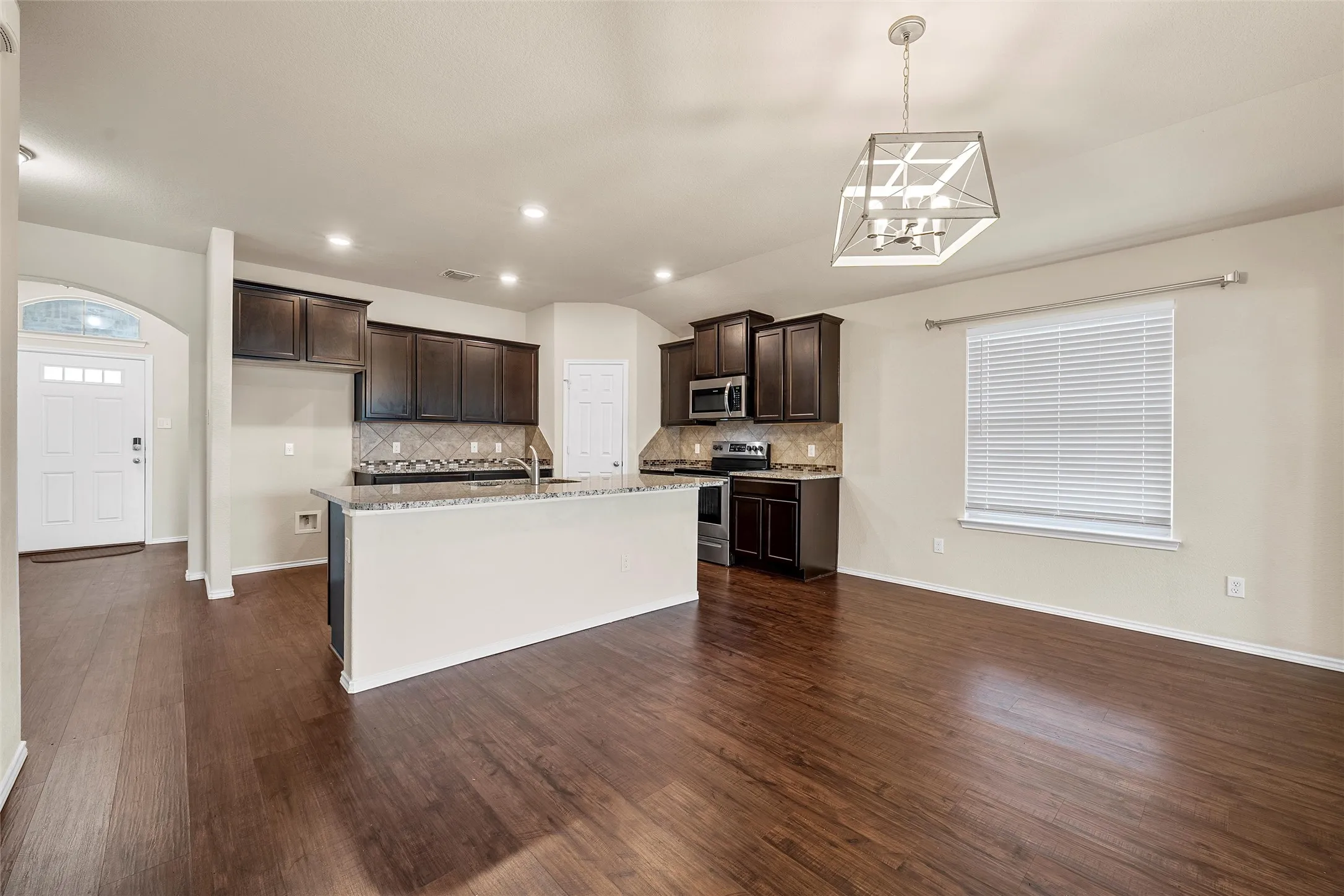 Kitchen with stainless steel appliances, dark brown cabinetry, tasteful backsplash, a kitchen island with sink, and recessed lighting
