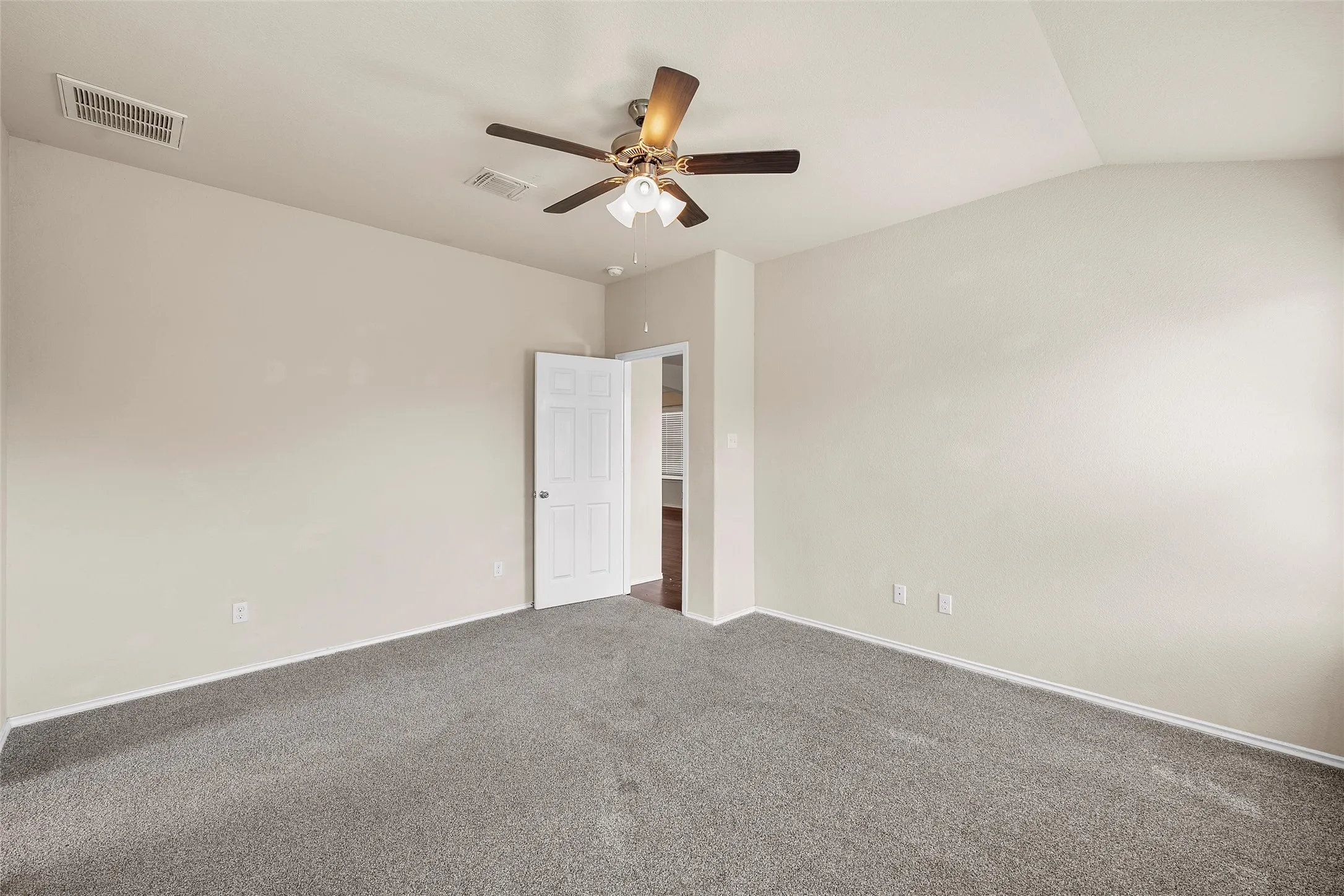 Carpeted empty room with ceiling fan and vaulted ceiling
