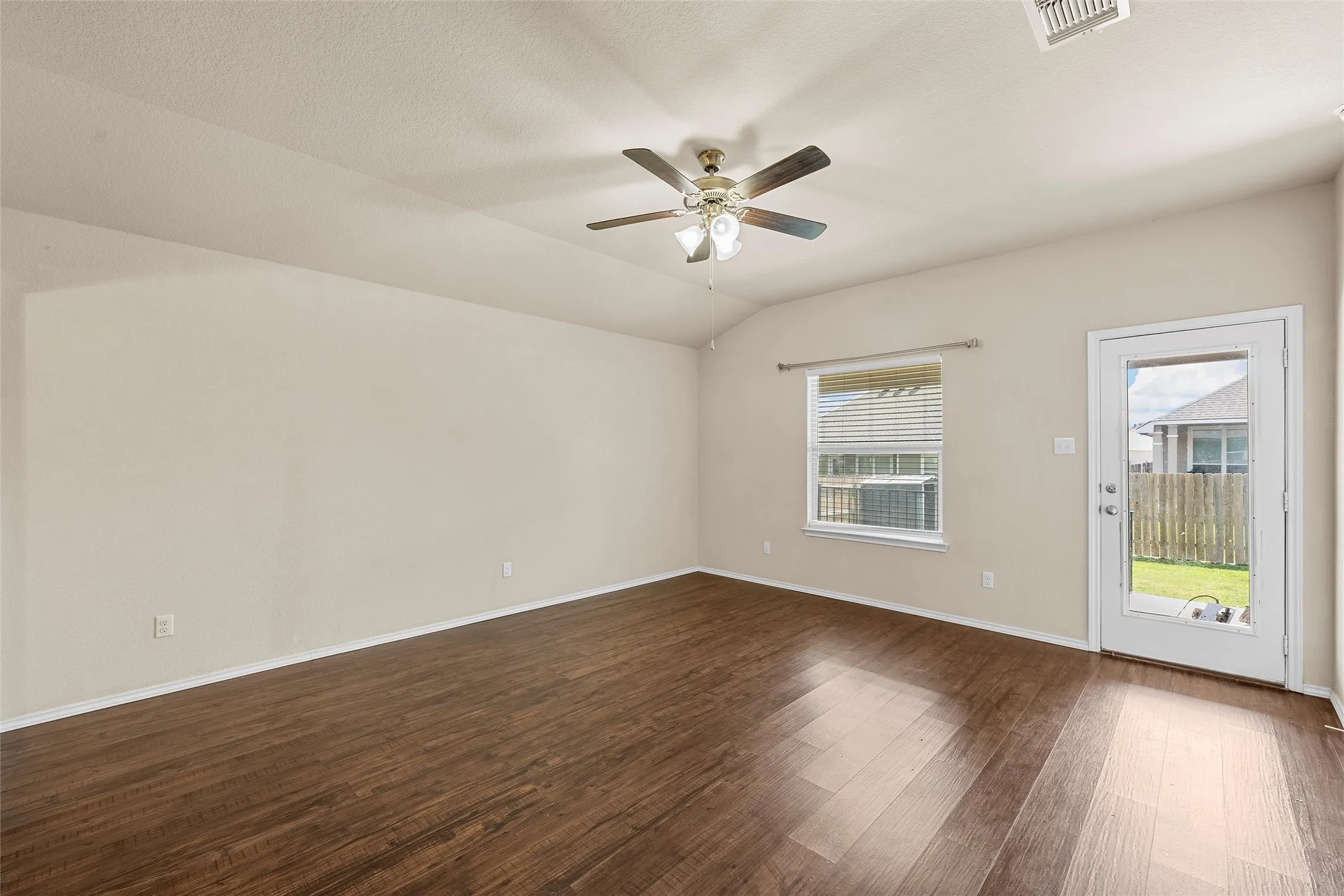 Empty room featuring dark wood finished floors, ceiling fan, and vaulted ceiling