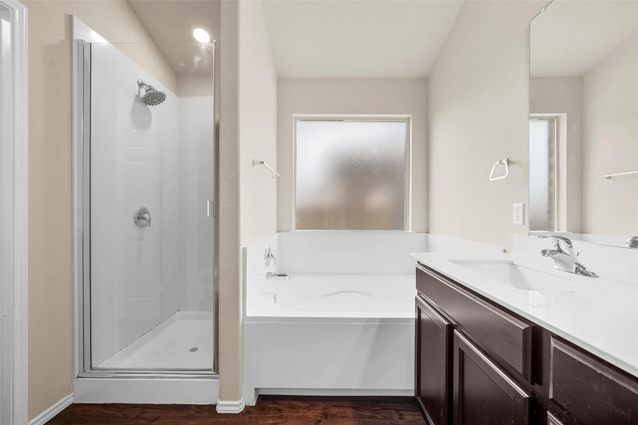 Full bathroom with a shower stall, a garden tub, vanity, and wood finished floors