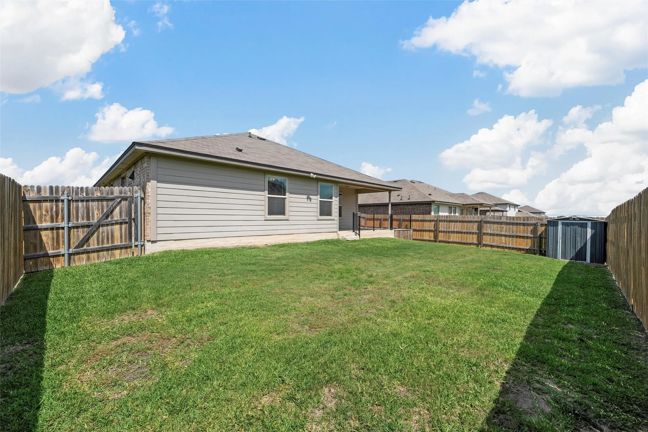 Back of house featuring a fenced backyard, a storage unit, and a patio