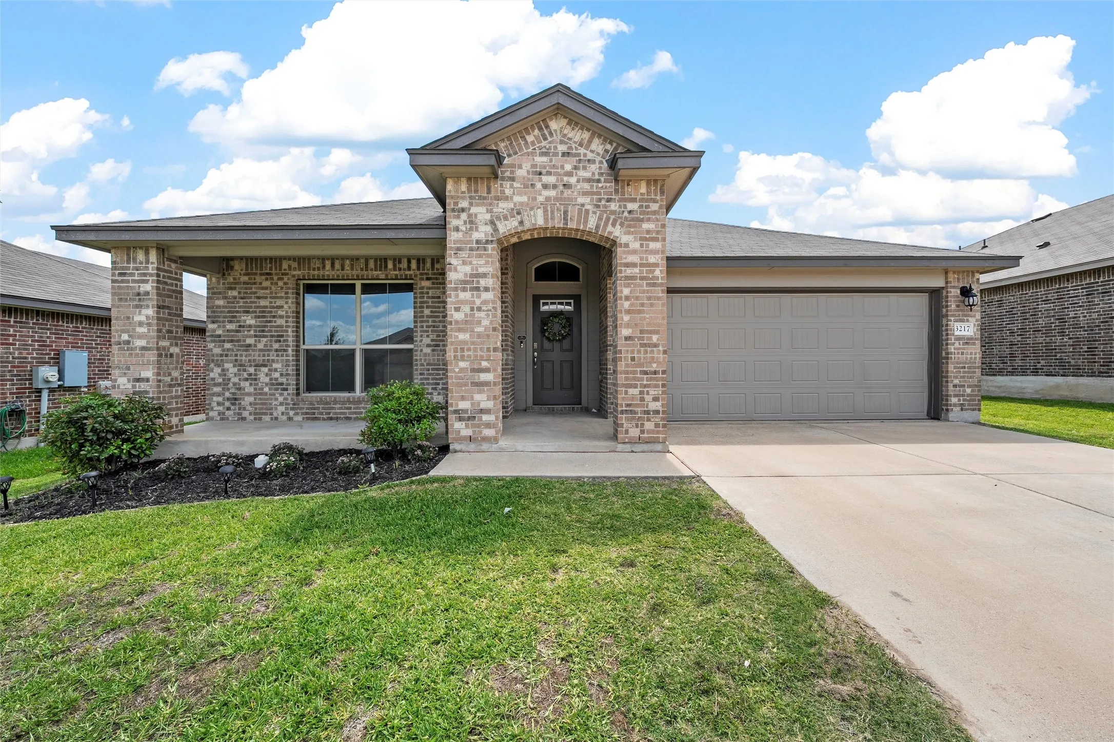 View of front facade featuring brick siding, an attached garage, and driveway