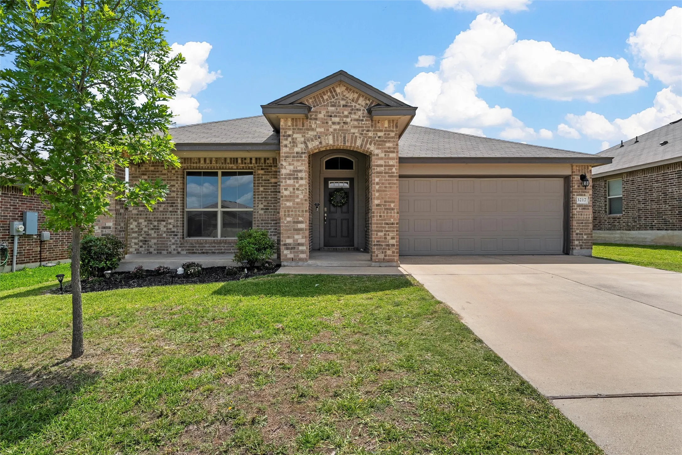 View of front of home with a garage, brick siding, a front yard, and driveway