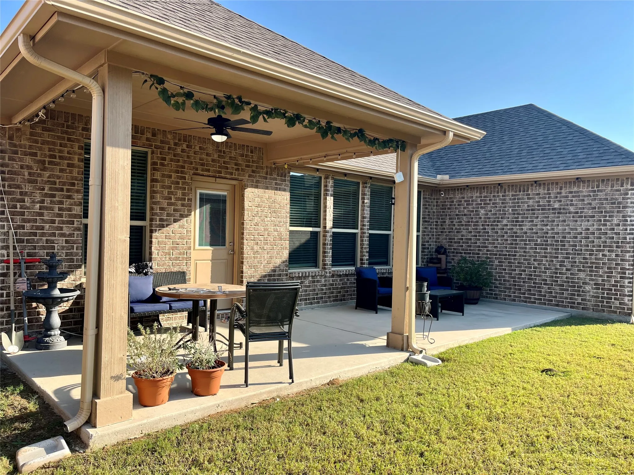 Covered concrete patio with a ceiling fan, recessed lighting, and brick exterior
