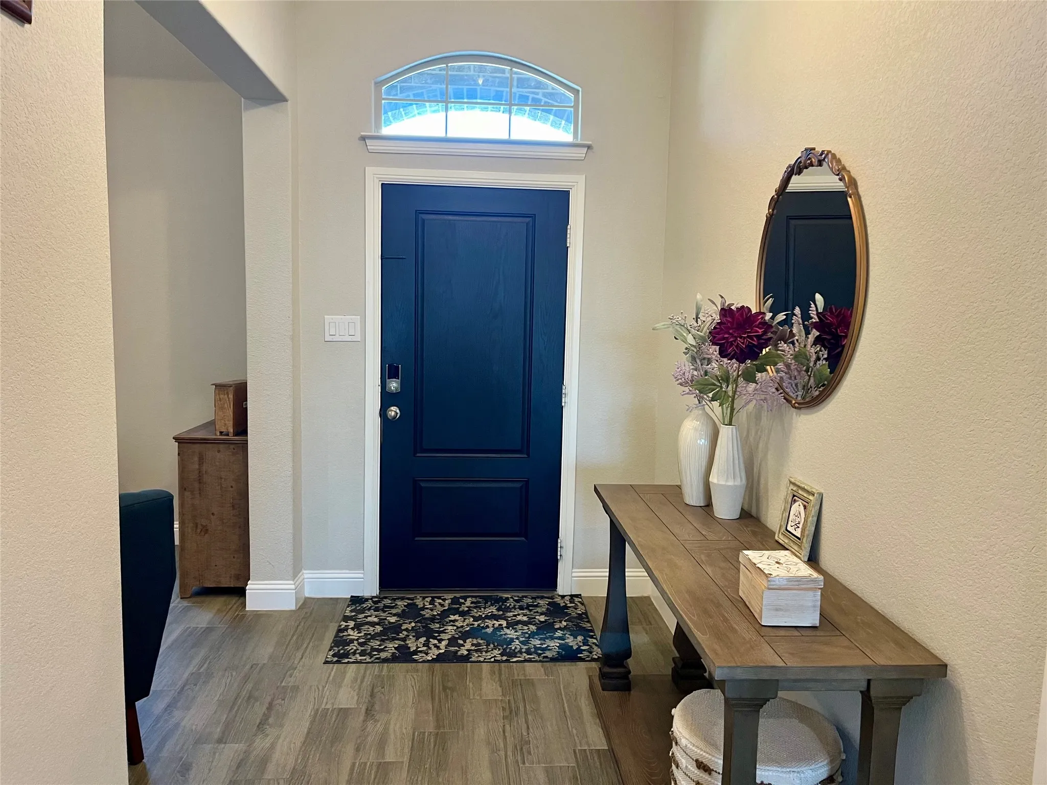 Entryway featuring a dark paneled door, an arched transom window, wood-finish flooring, and white baseboards